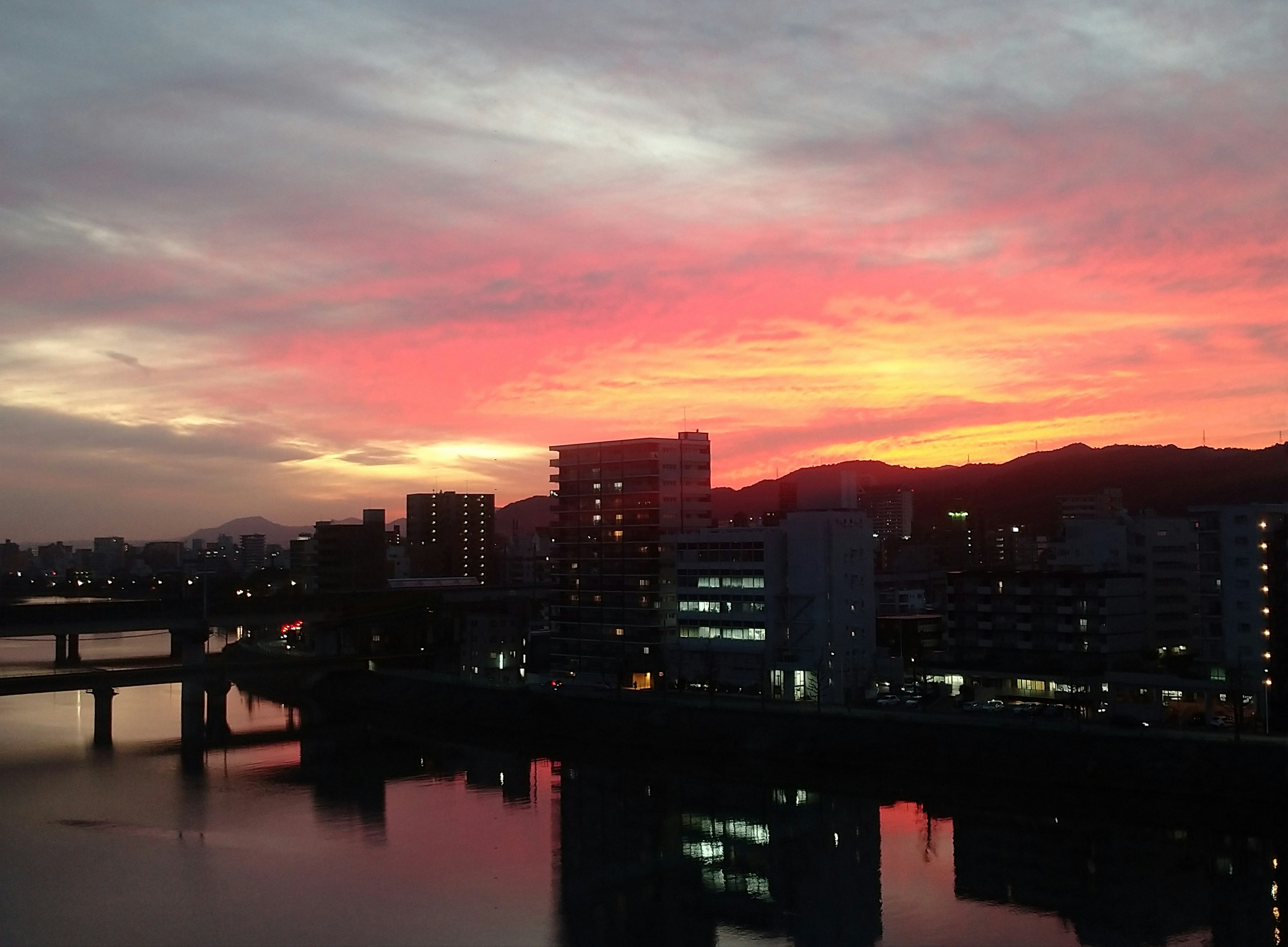 Cityscape at sunset with vibrant colors reflected in the water