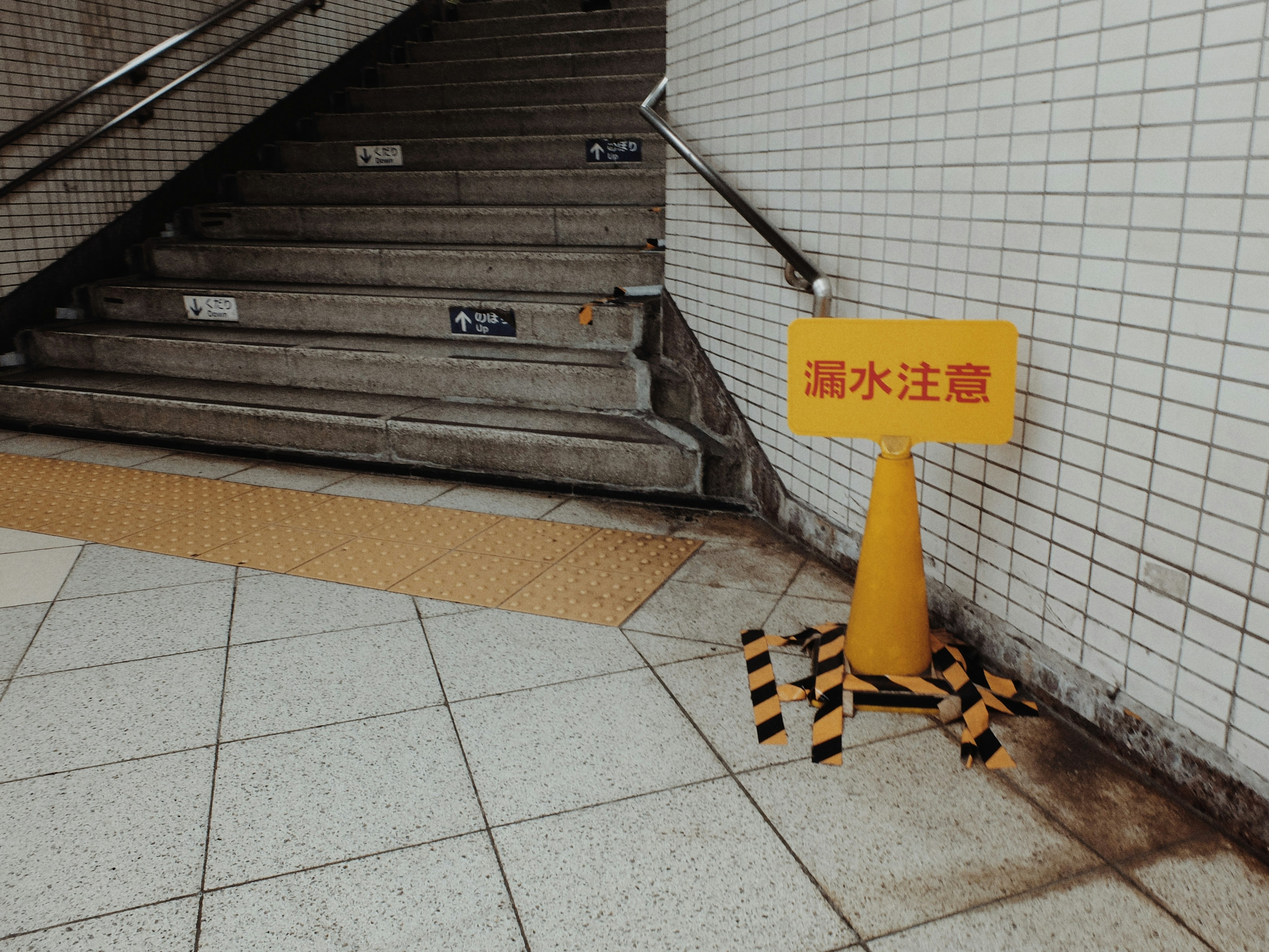 Gelbes Warnschild vor Wasser in der Nähe der Treppe mit schwarzem und gelbem Band