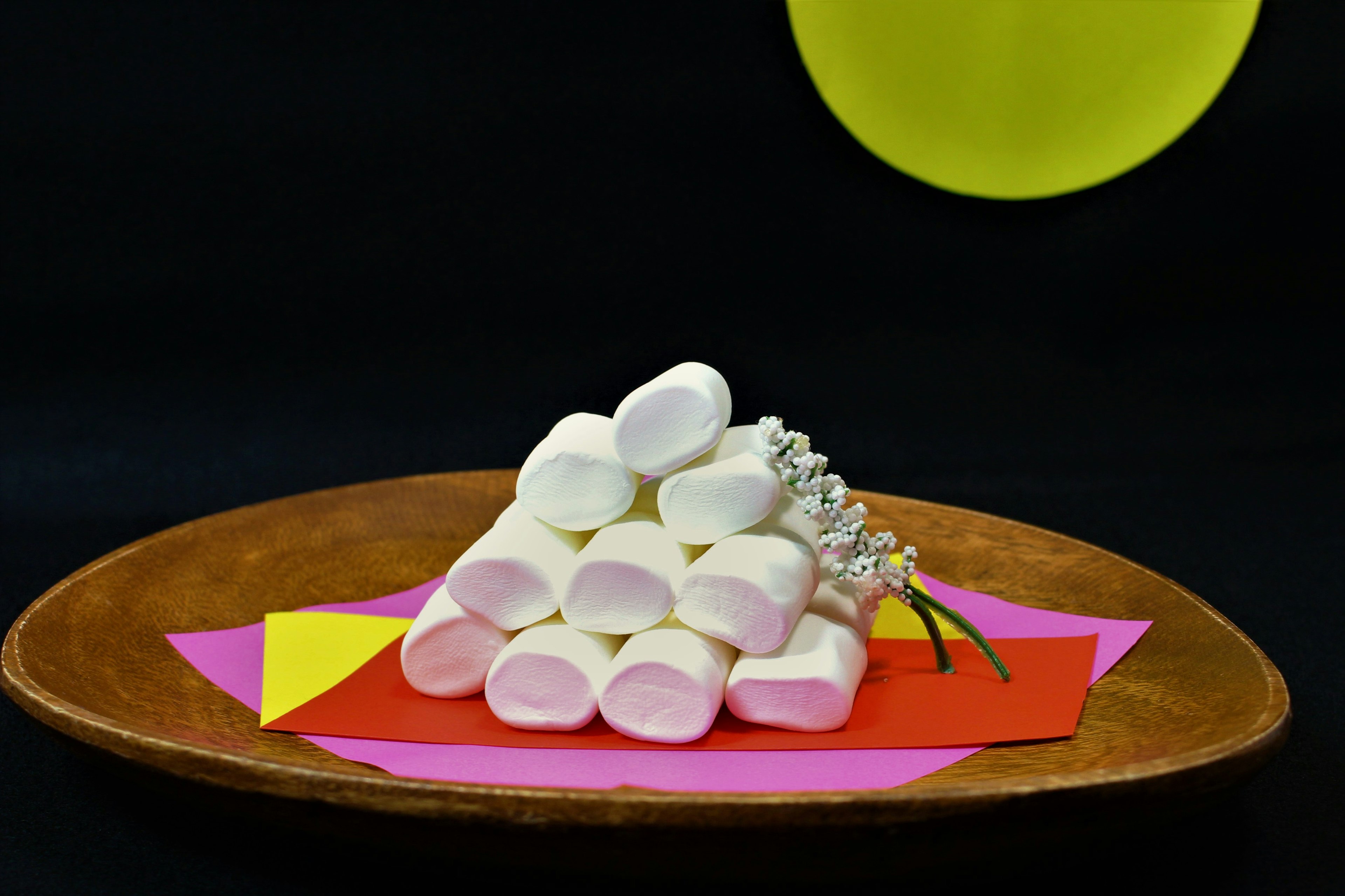 Una piramide di marshmallow su carta colorata con un cerchio giallo sullo sfondo