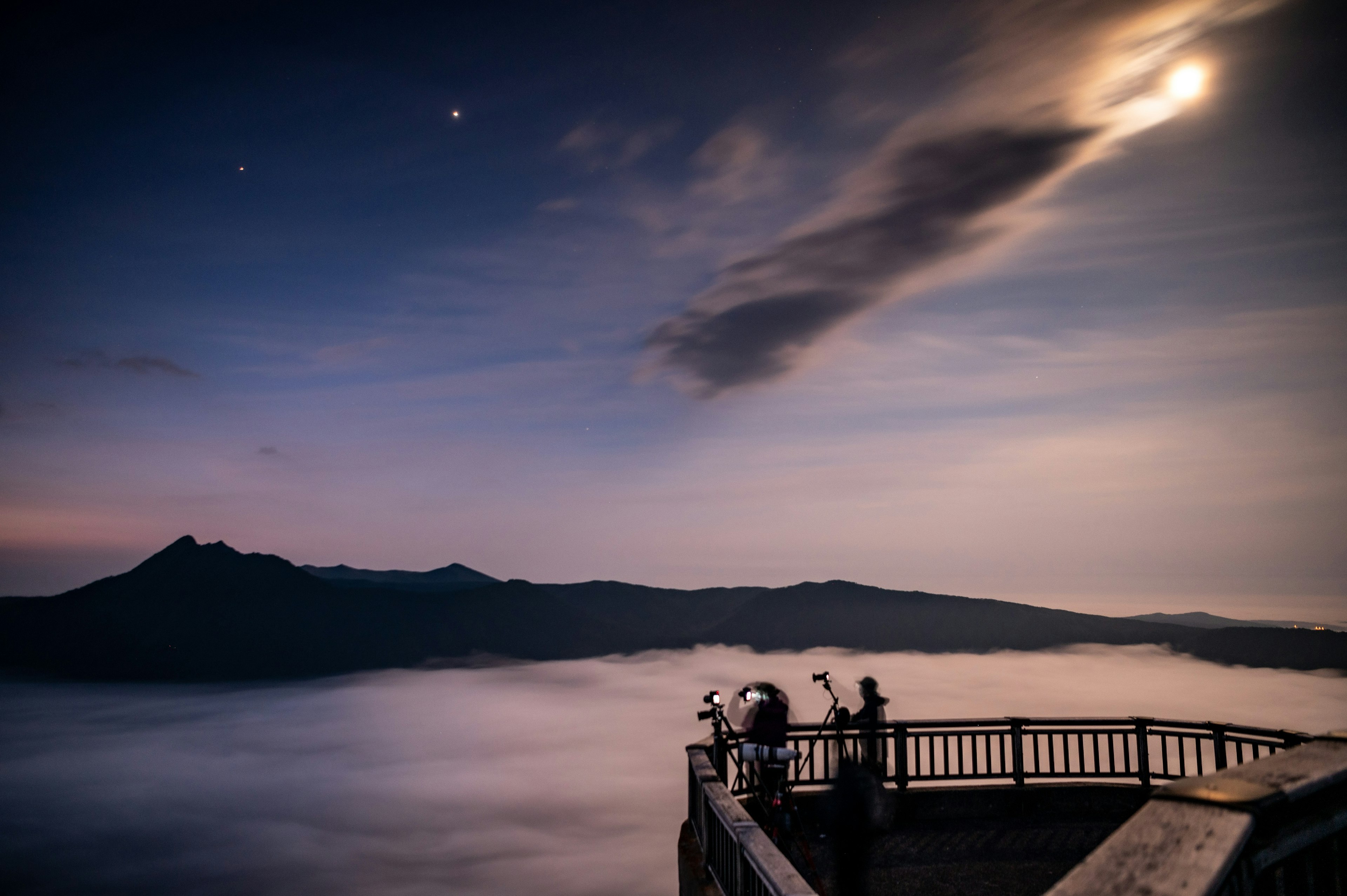 夜空中有月亮和星星的山景在雲海之上