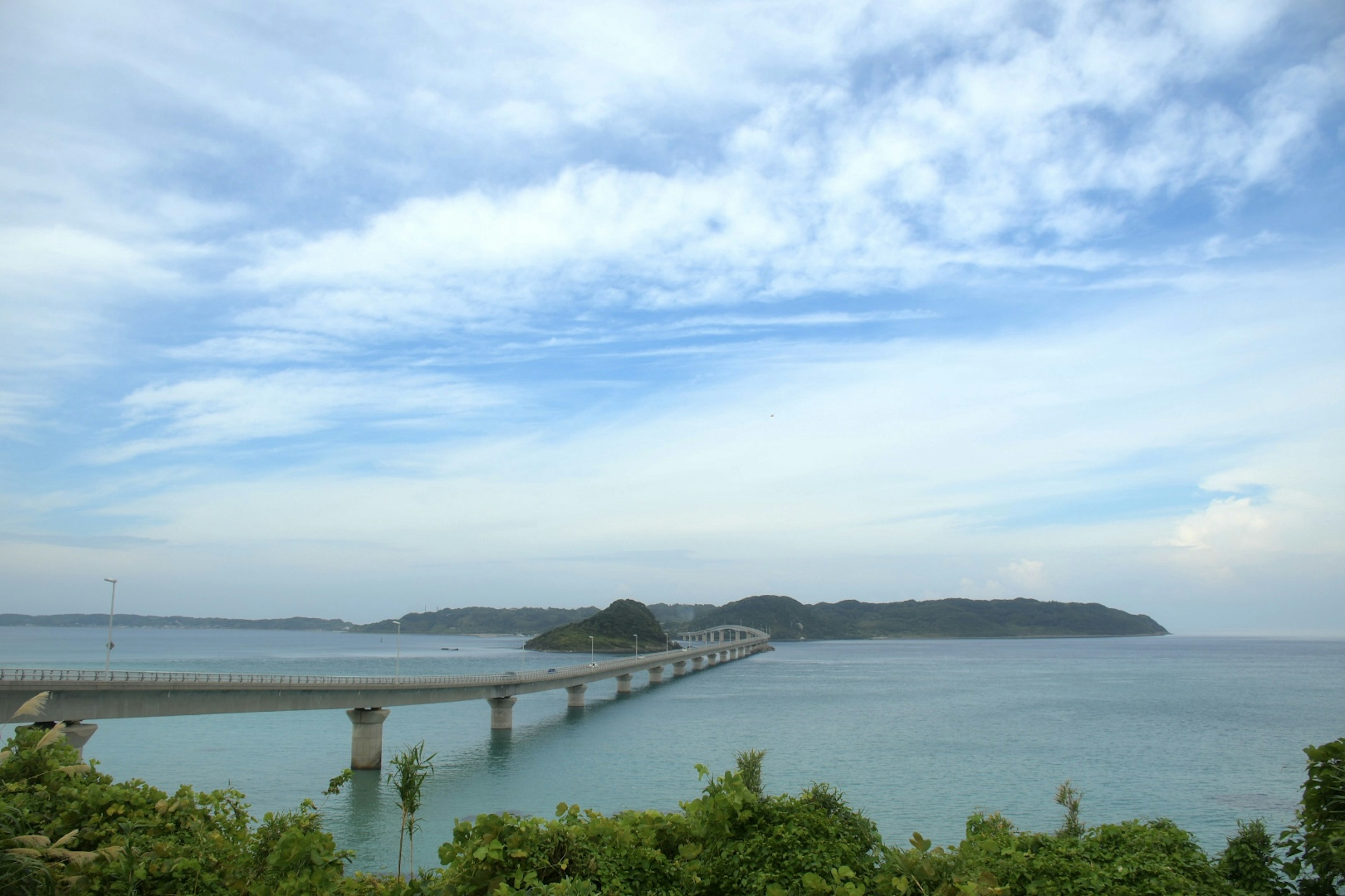 美丽的桥梁景观延伸在水面上，背景有岛屿