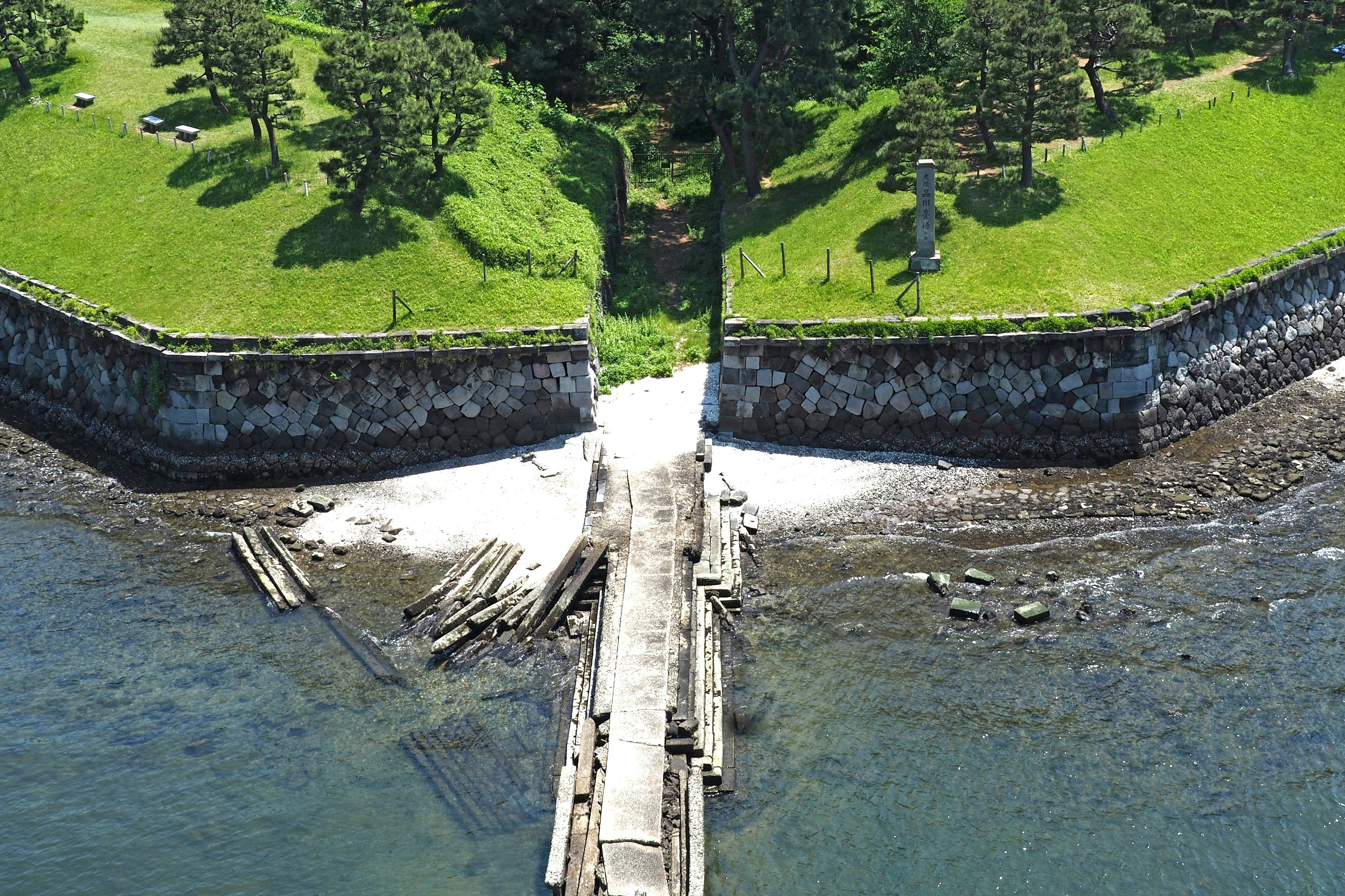 Aerial view of a green landscape with a pier and rocky shoreline