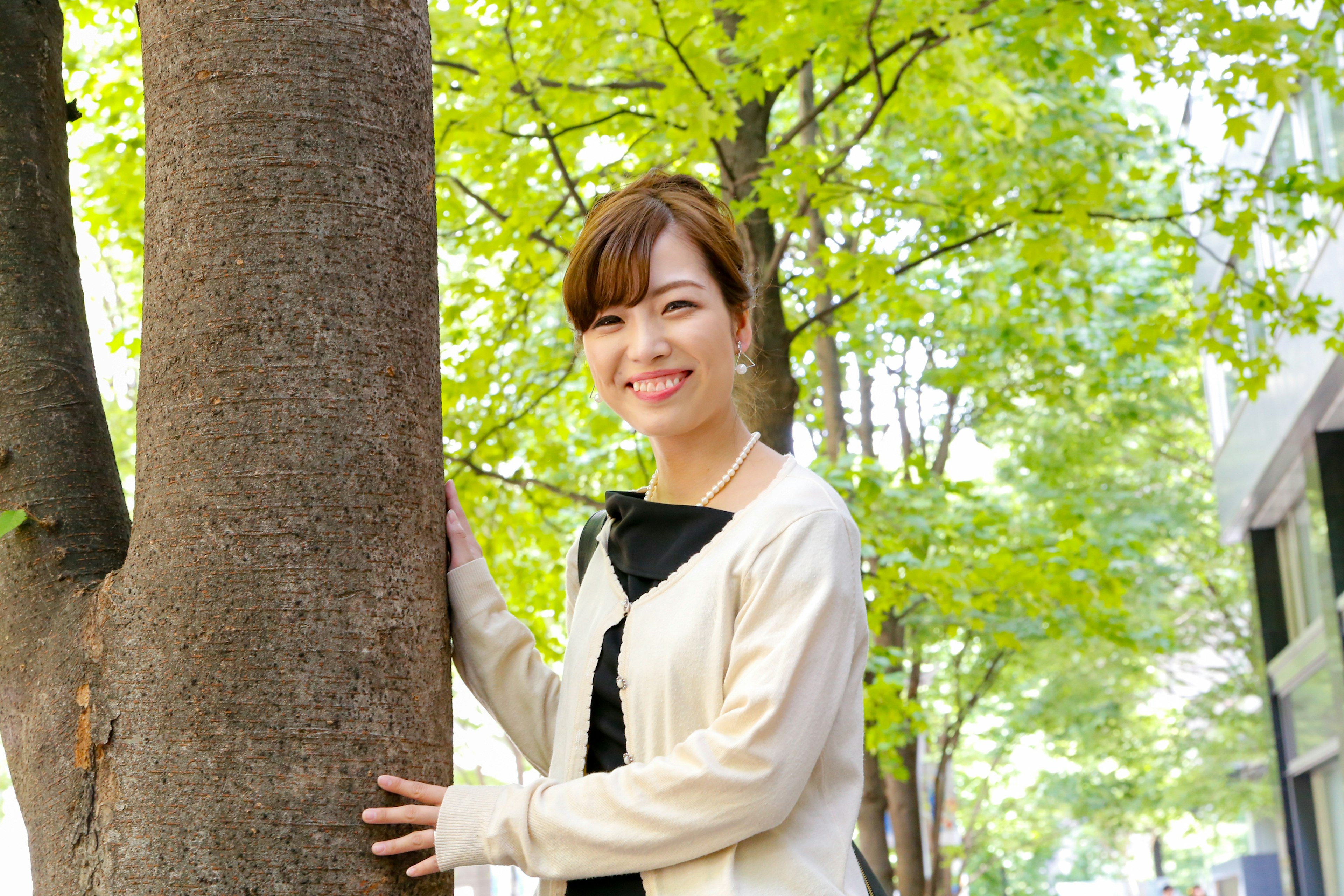 Smiling woman leaning against a tree among green foliage