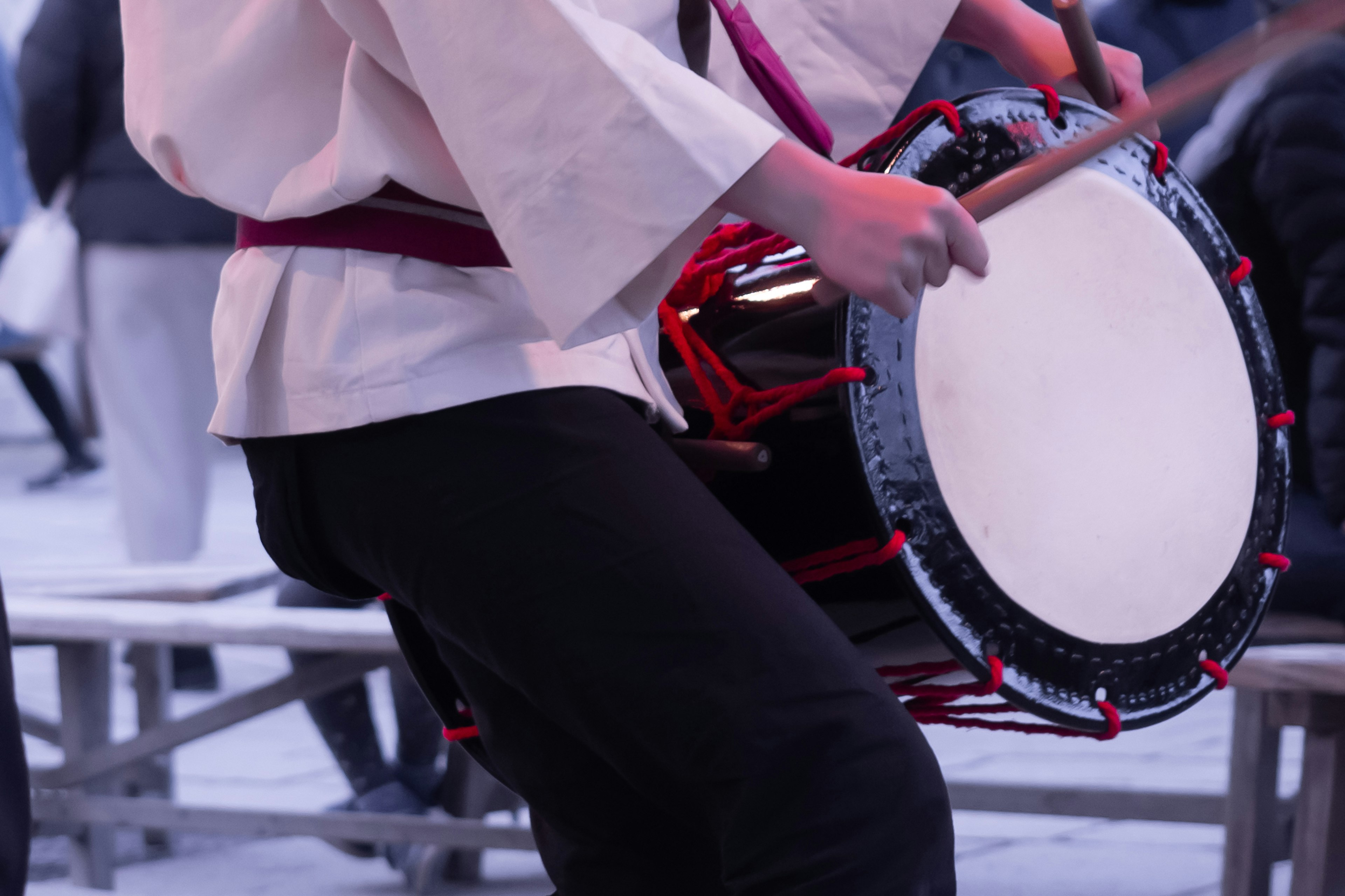 Person in traditional attire playing a red drum