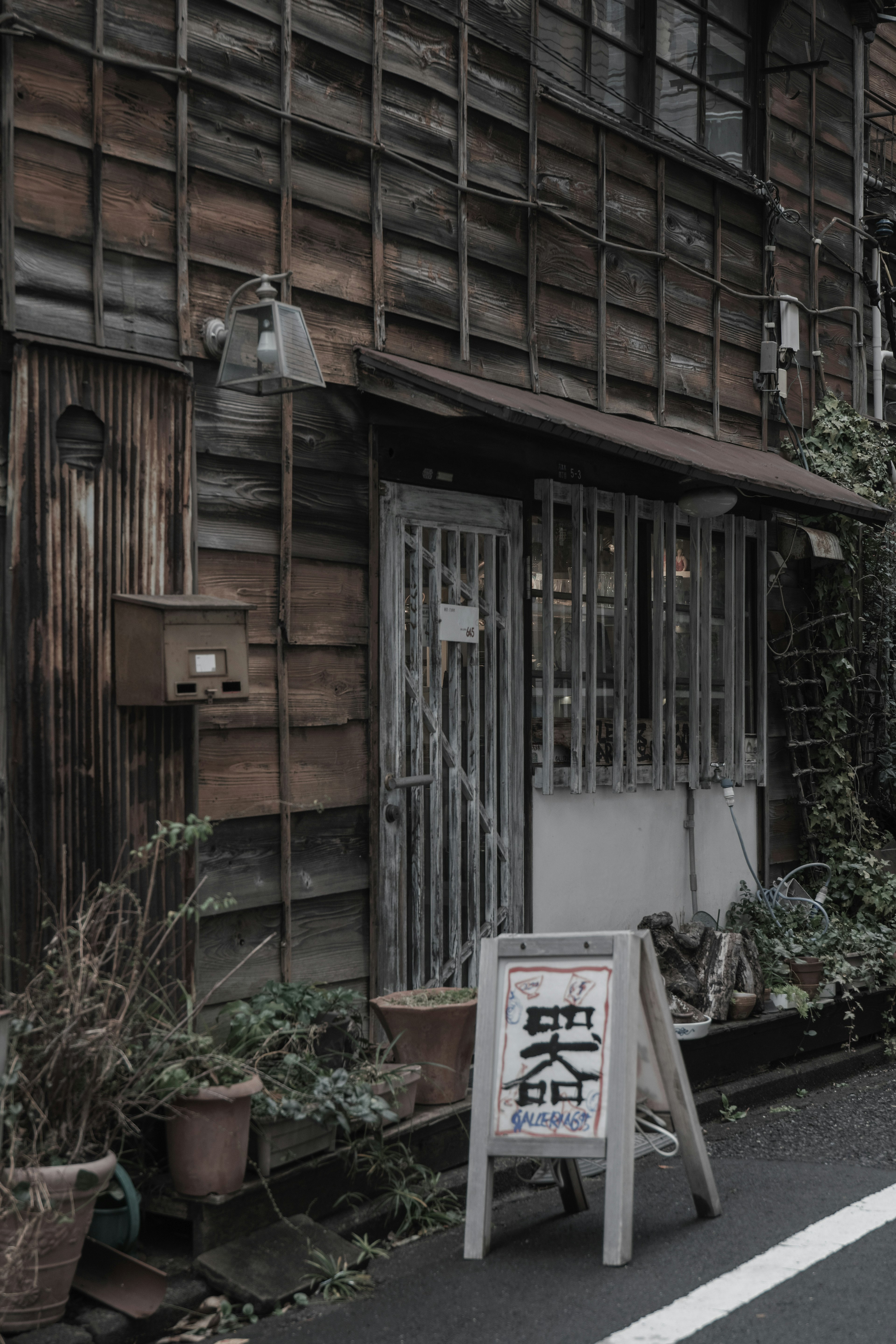 Old wooden building with plants and entrance sign