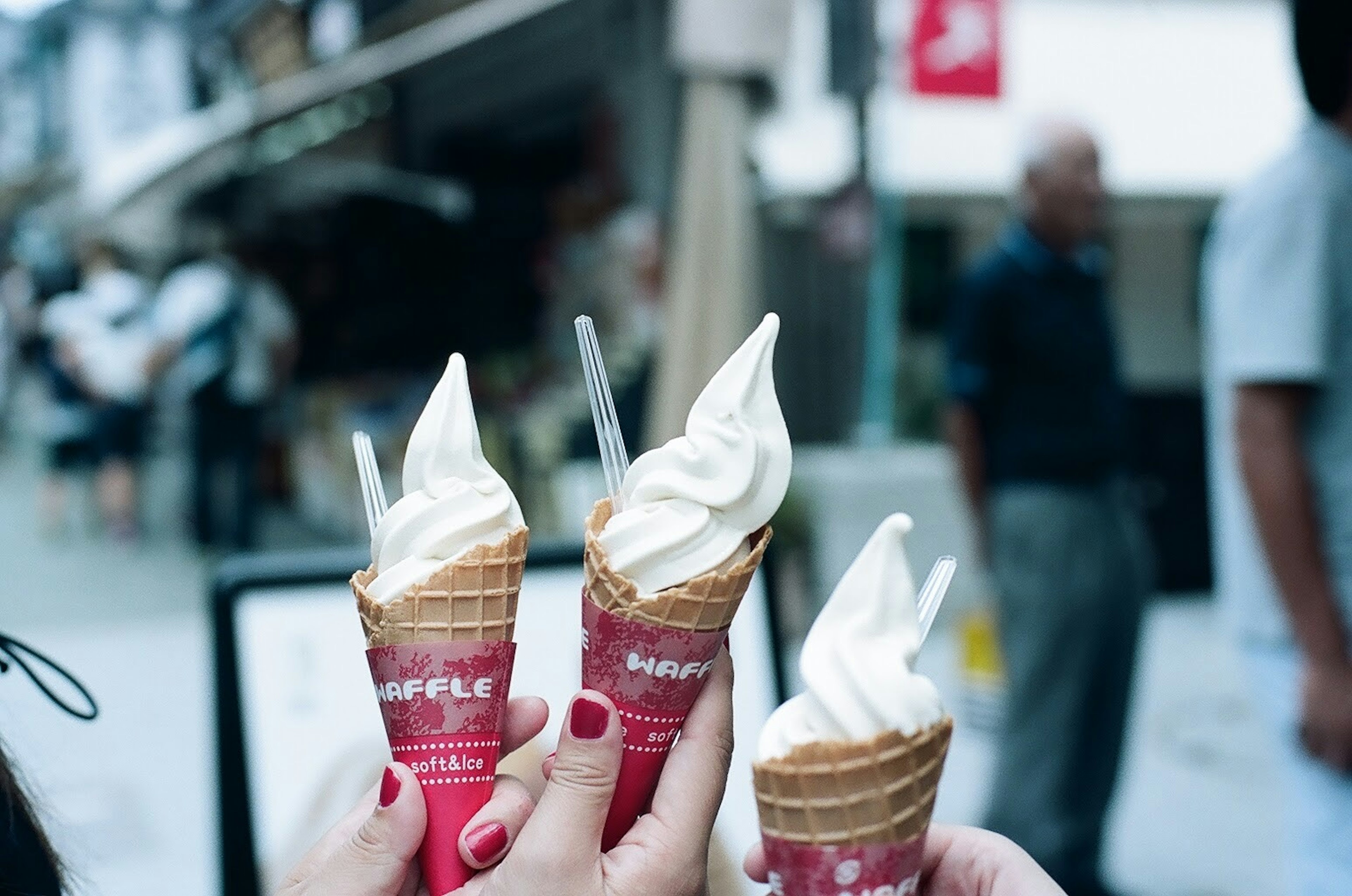 Tre coni gelato tenuti in mano con gelato morbido