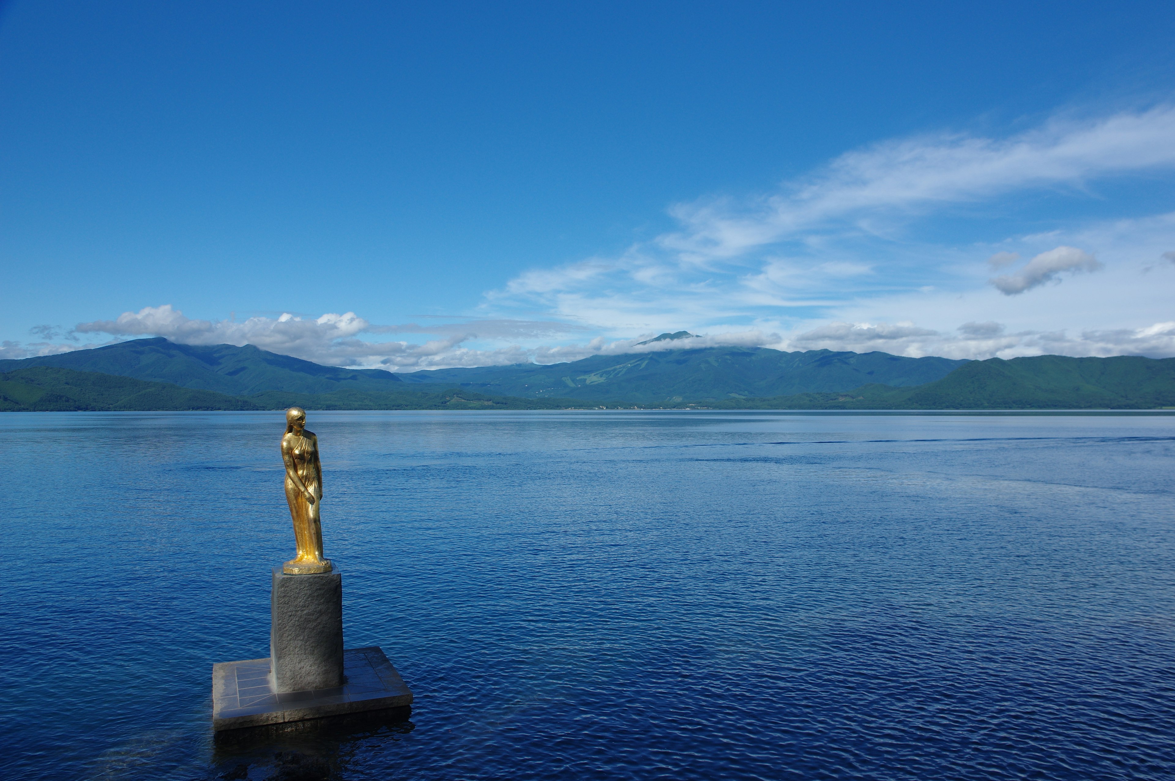 Estatua dorada junto al lago con cielo azul