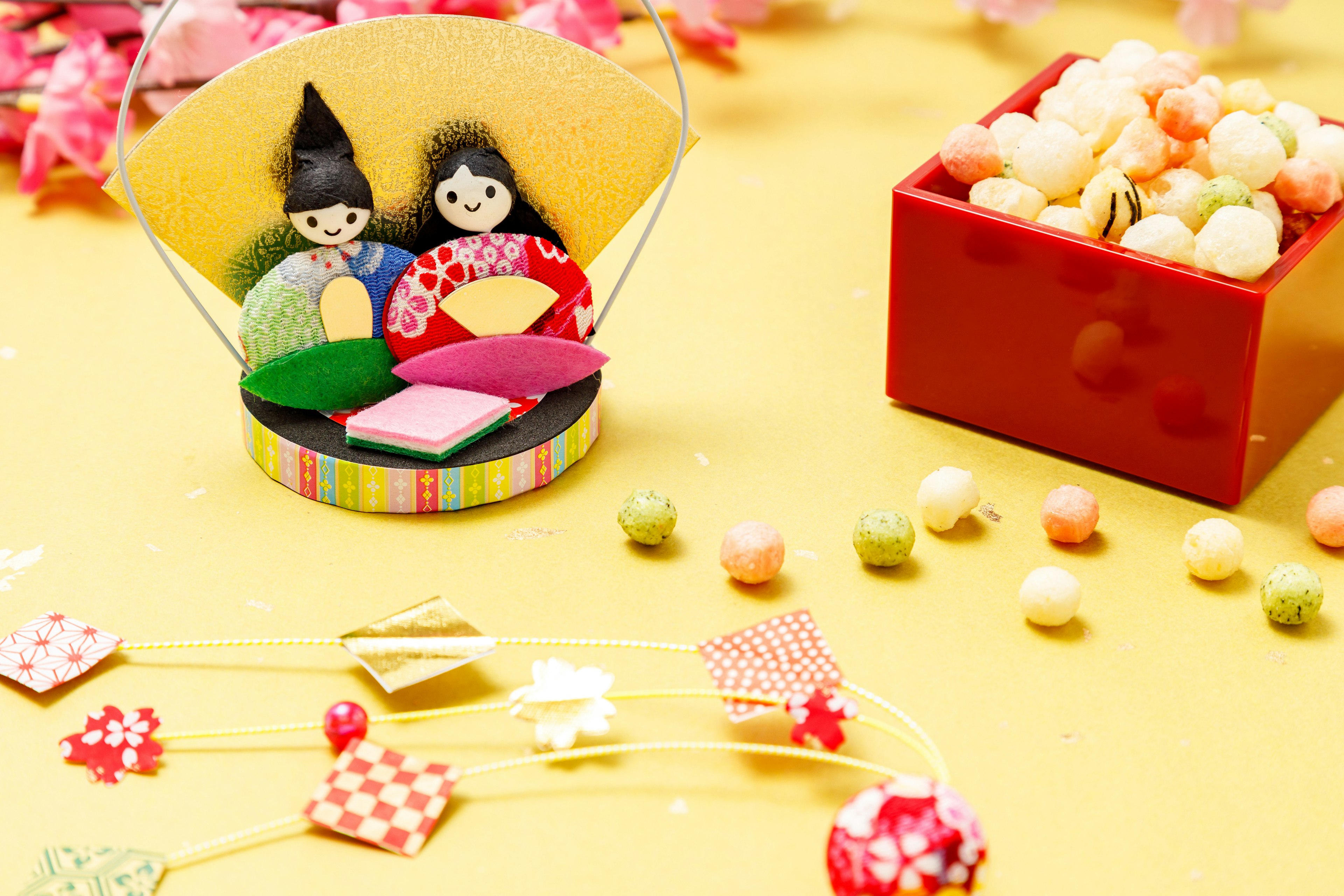 Two dolls sitting on a yellow background with colorful candy boxes