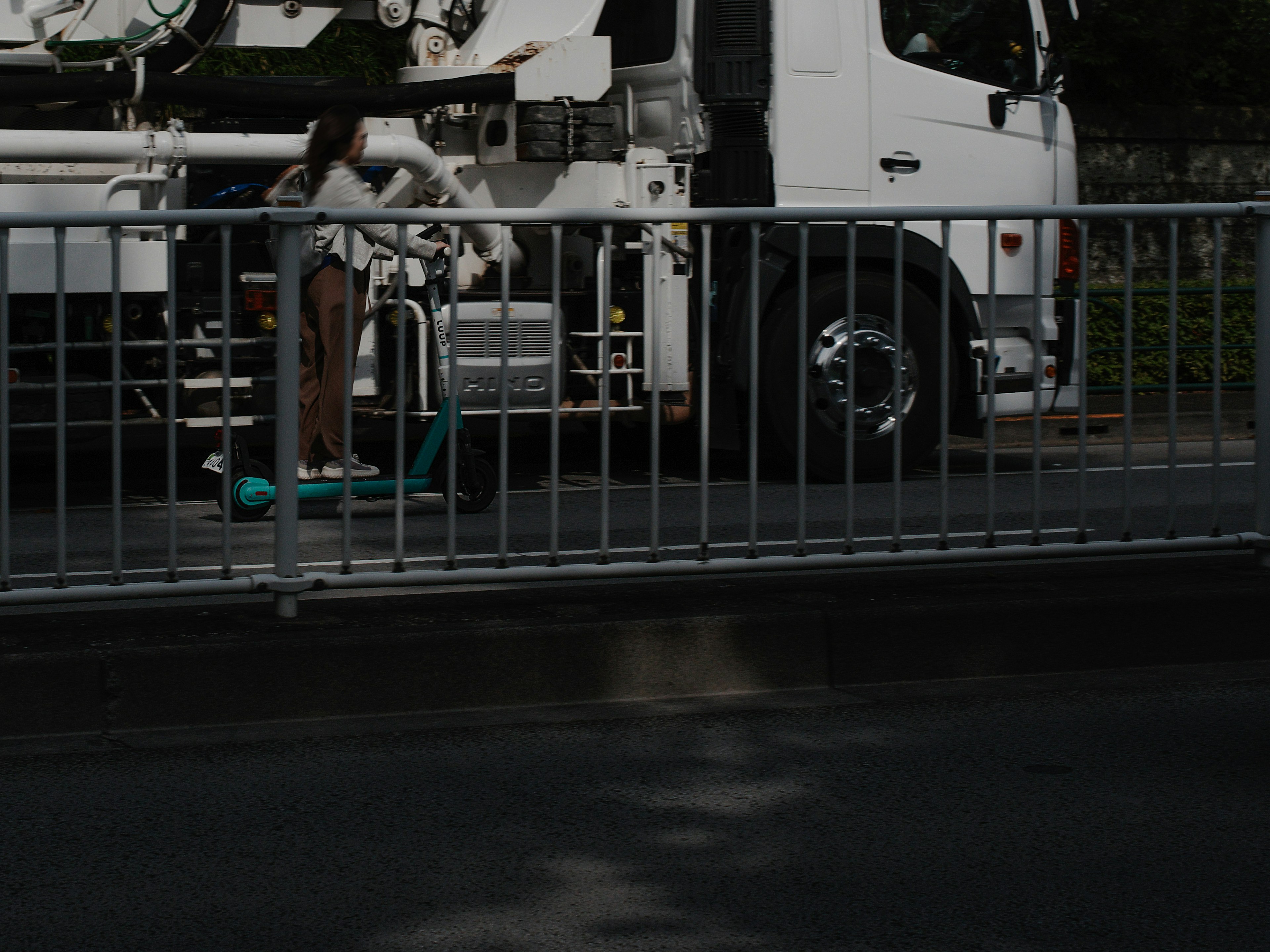 A woman standing near a white truck and a blue scooter