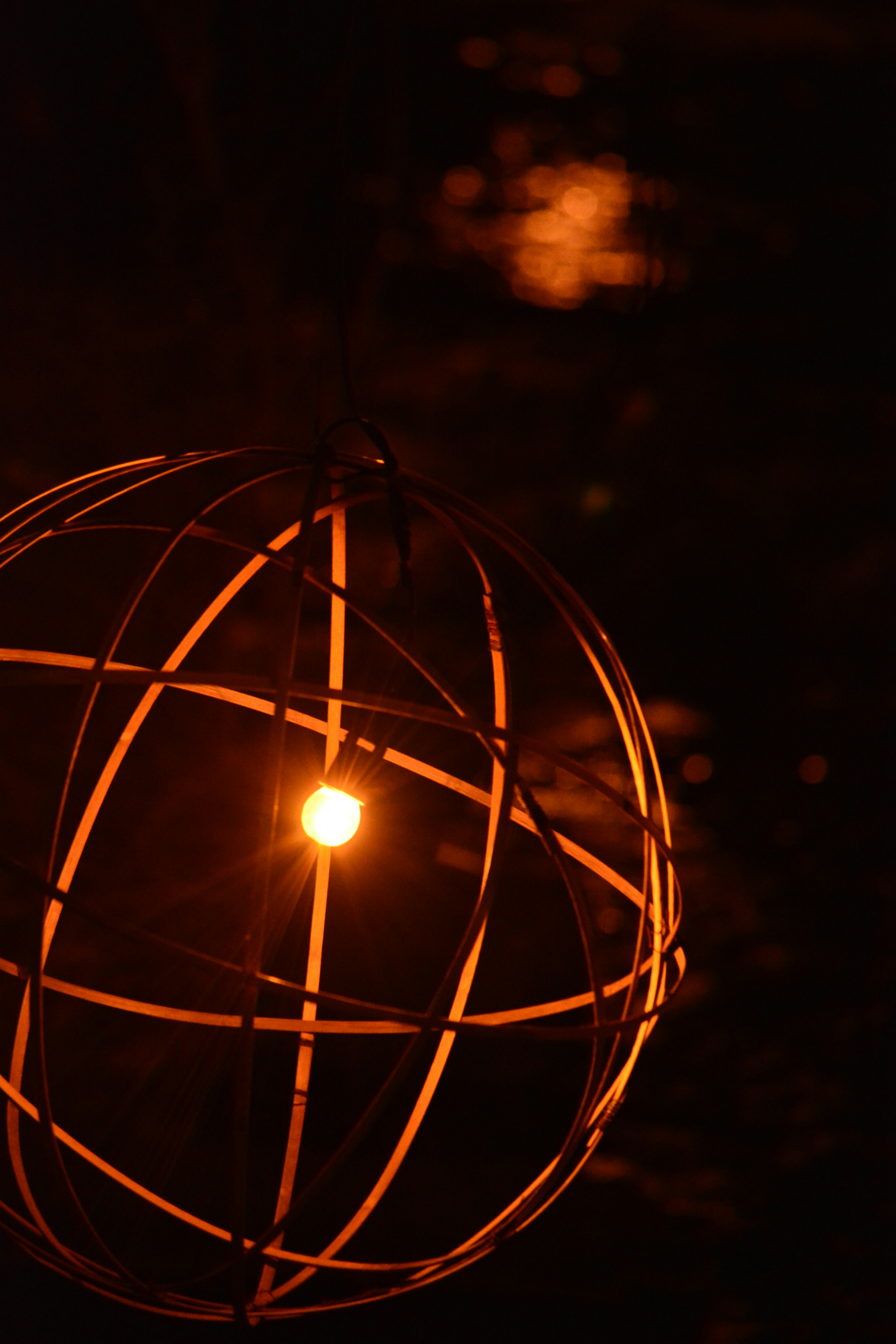 Una lámpara esférica con luz naranja brillando sobre un fondo oscuro