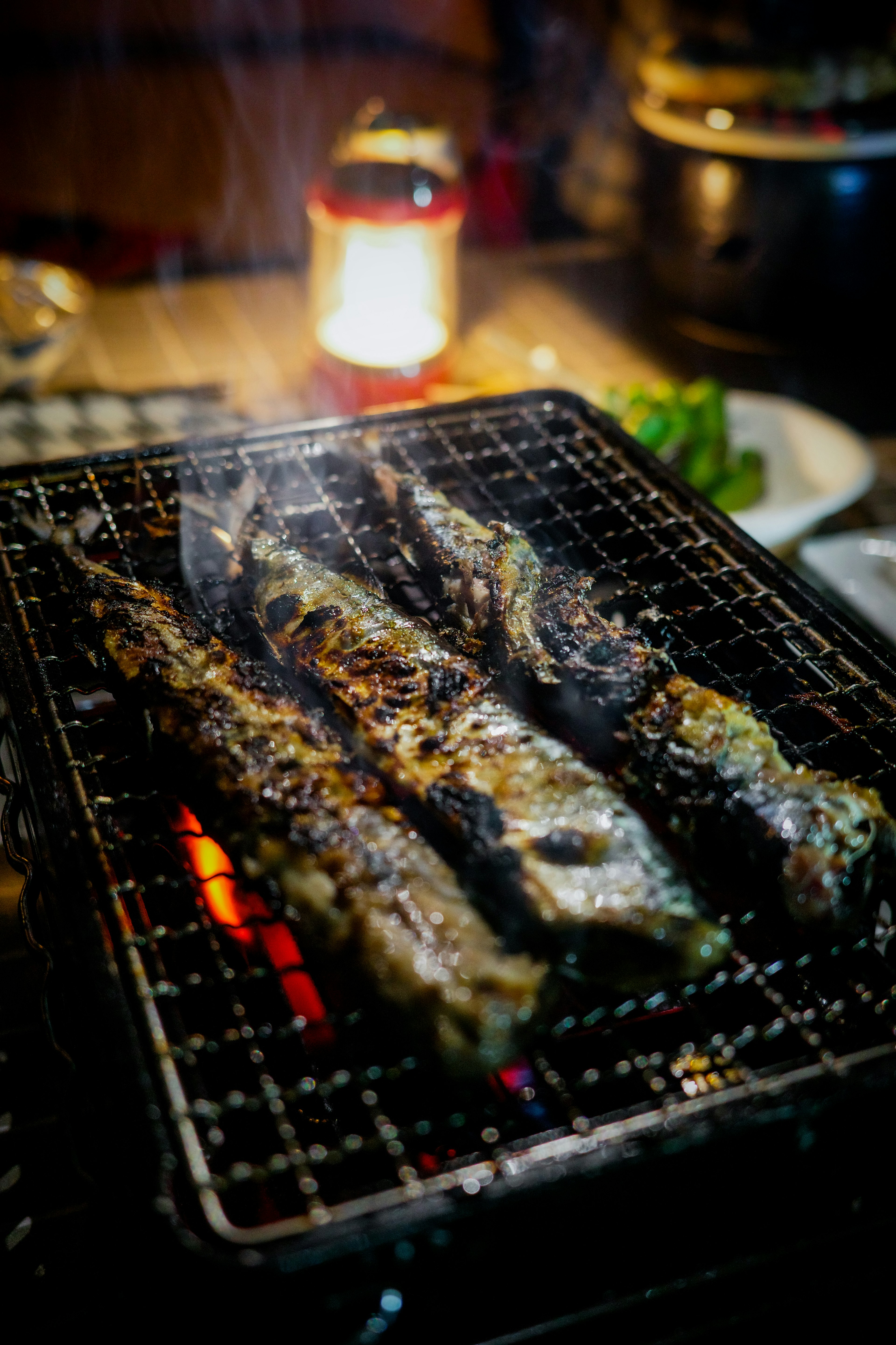 炭火で焼かれた魚の串焼きが煙を上げている