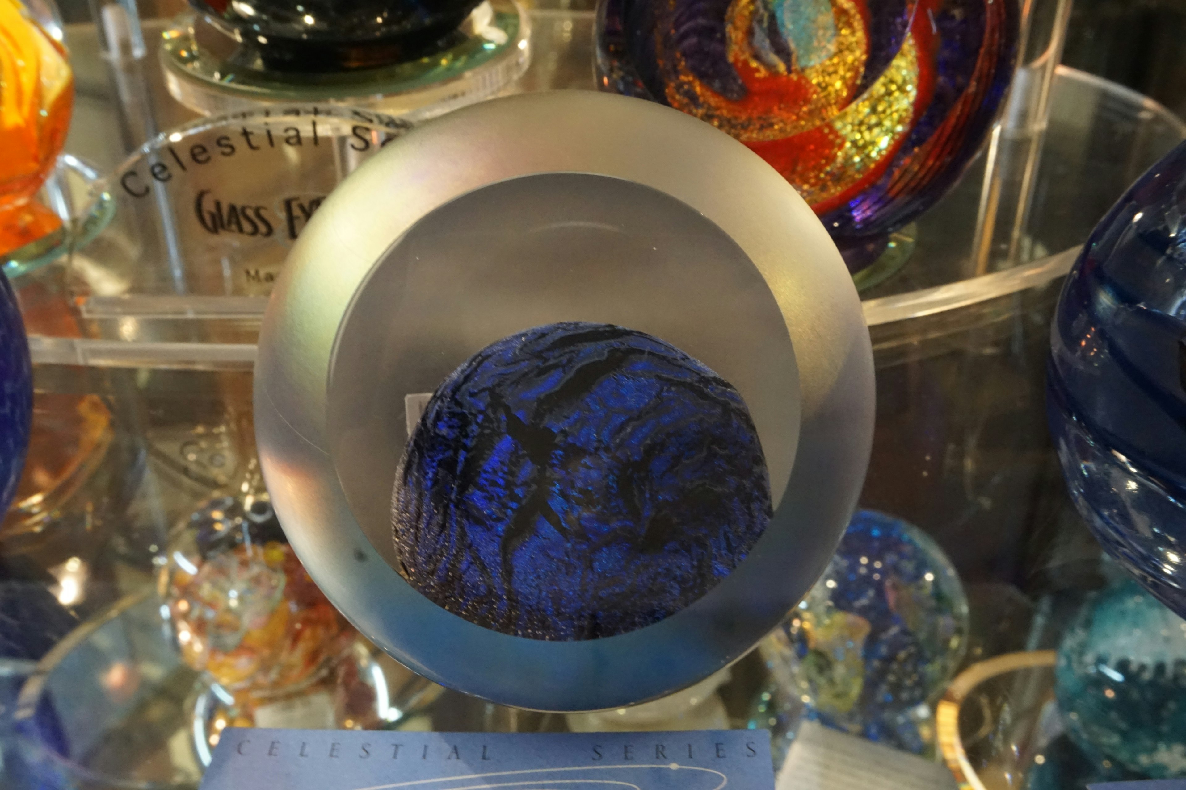 A blue glass orb placed on a transparent circular base