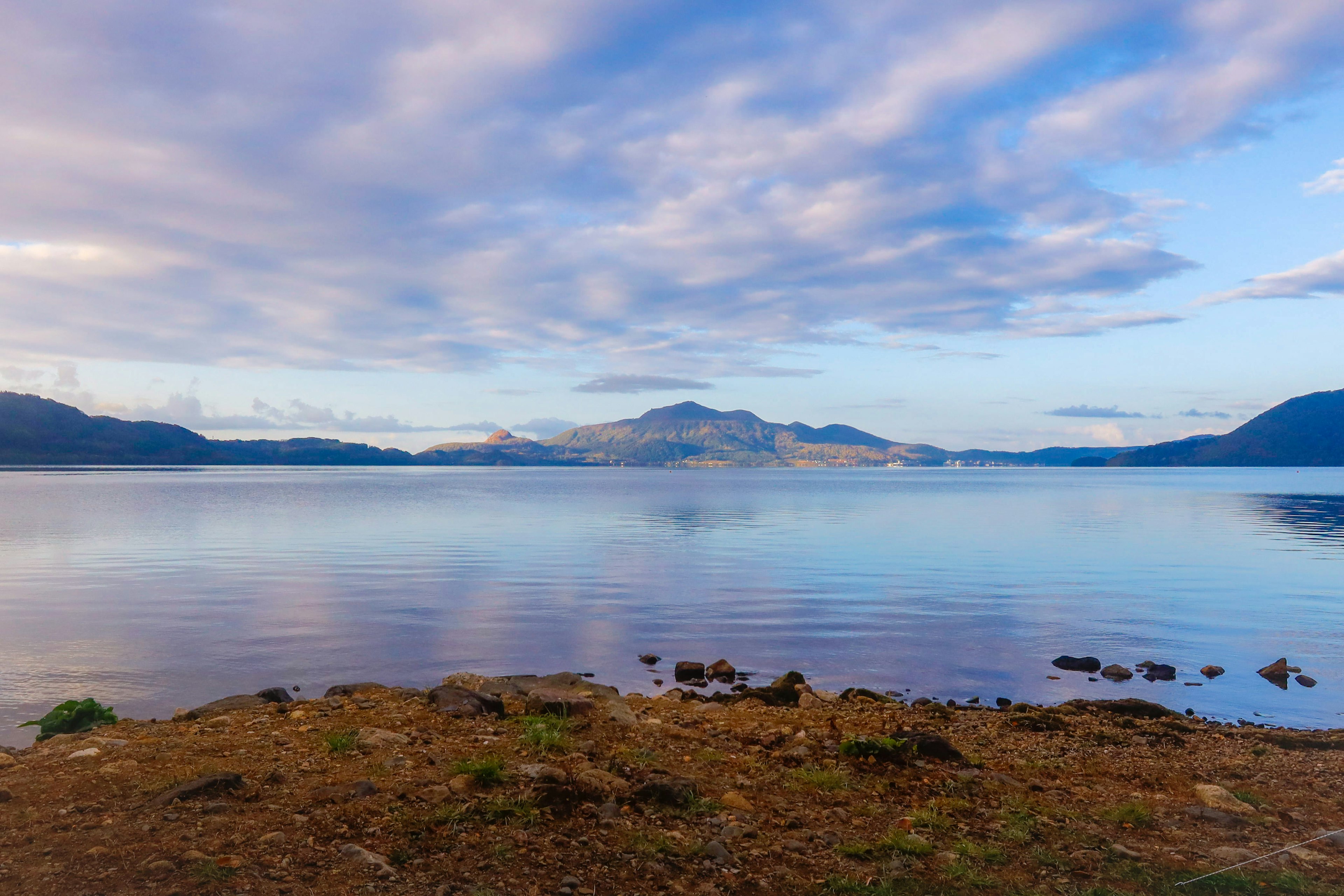 Calm lake view with blue sky and distant mountains