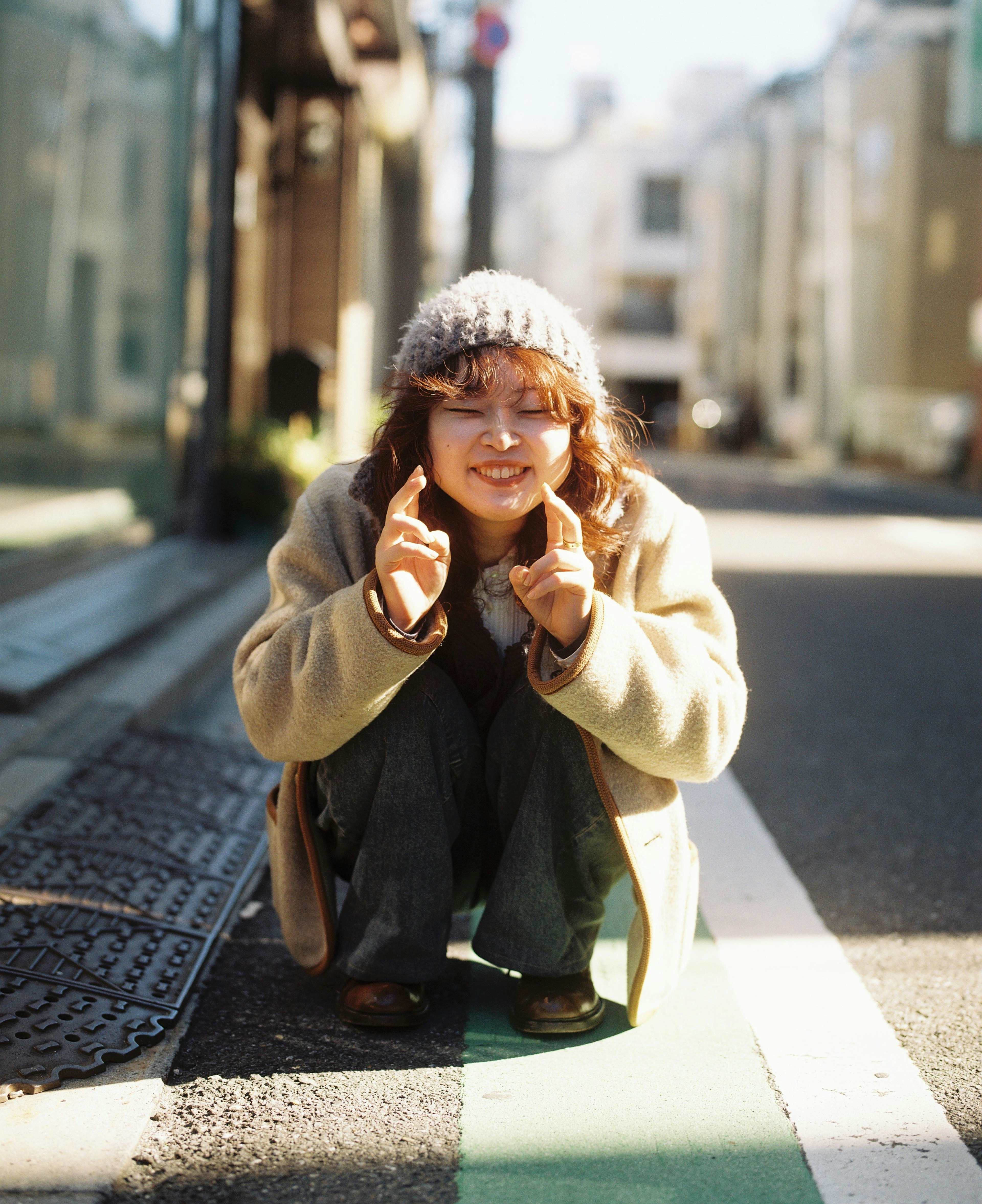 Una mujer posando en la calle con un gorro de lana y sonriendo mientras señala con el dedo