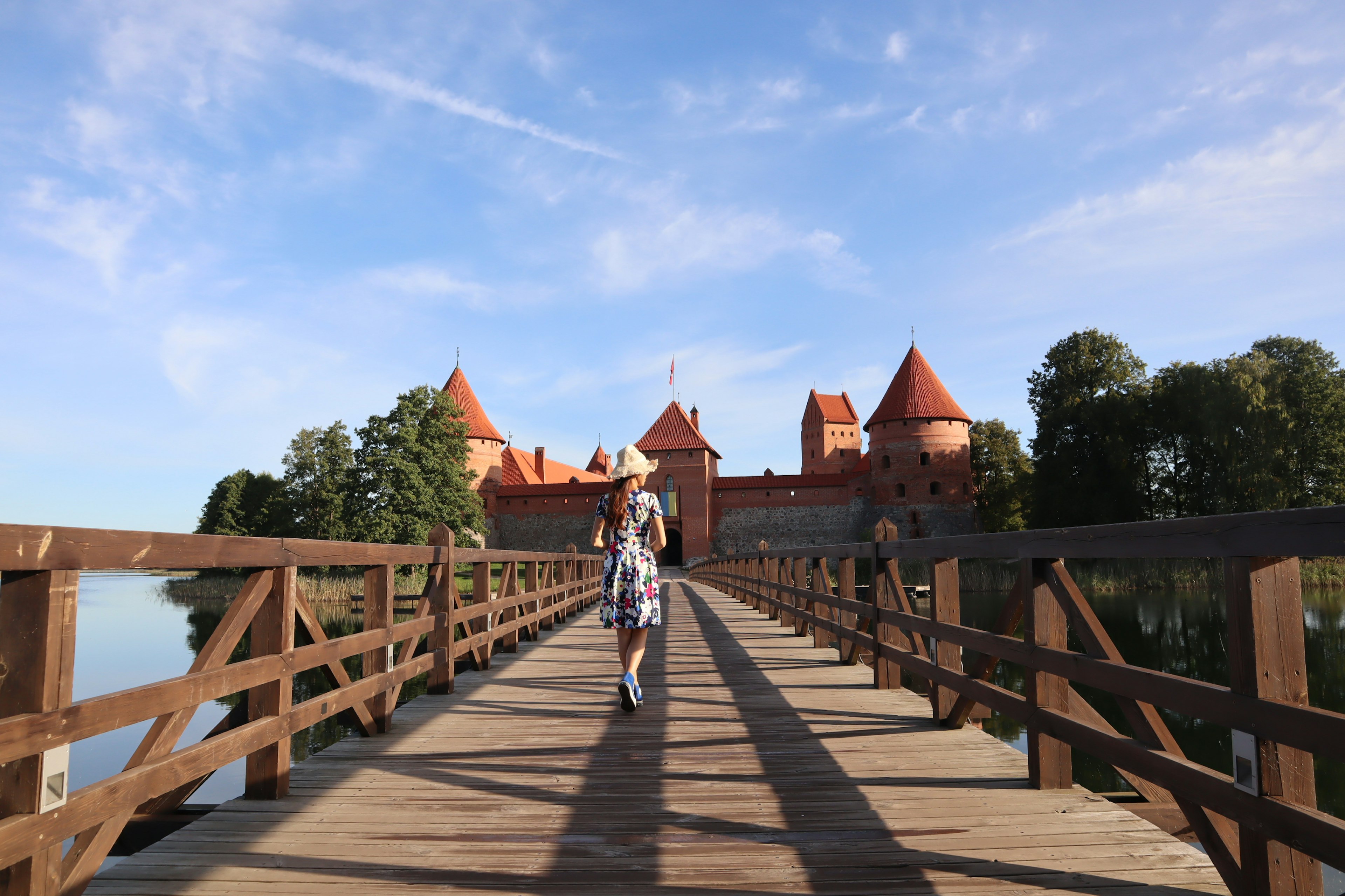 Persona caminando por un puente de madera hacia un hermoso castillo