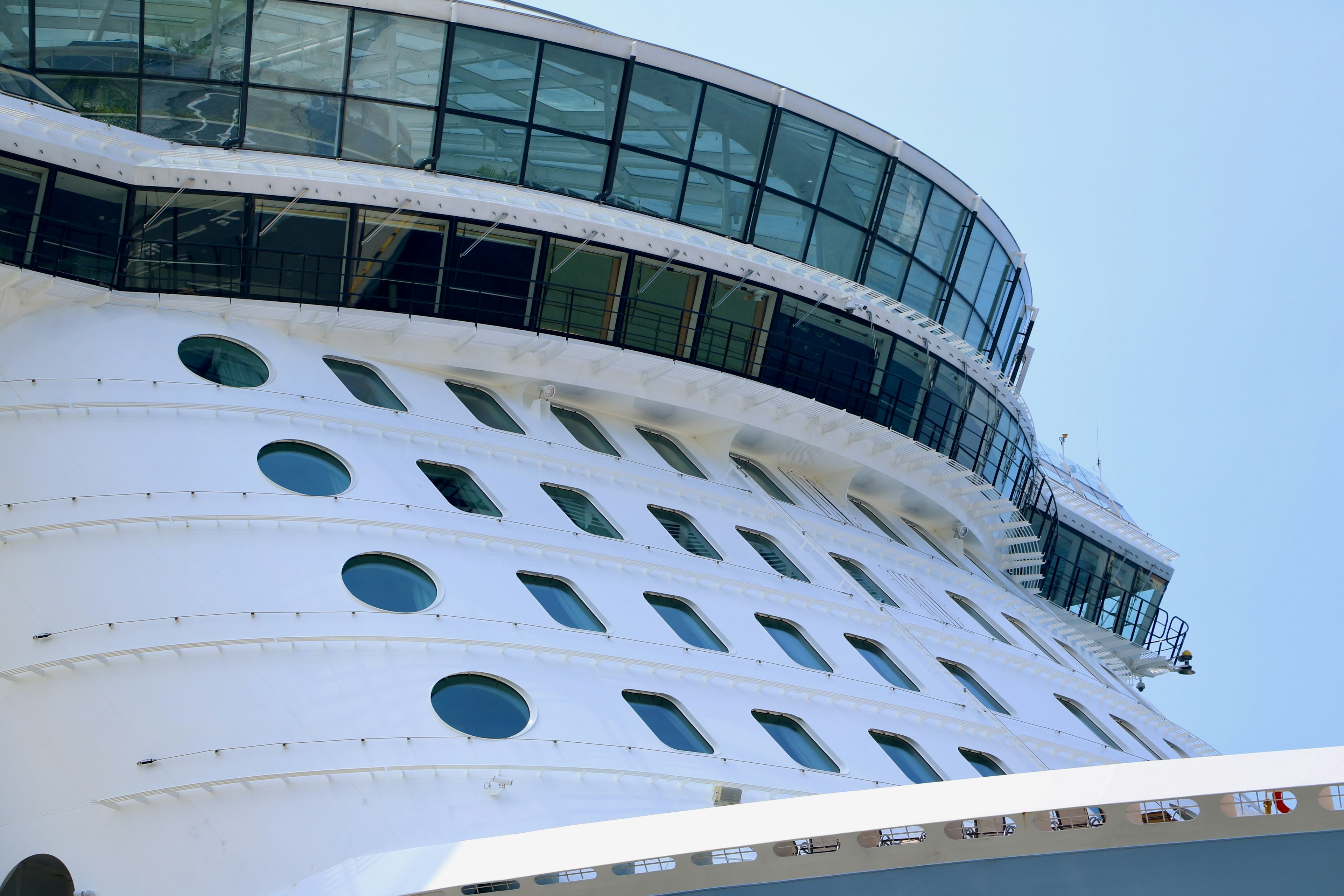 Close-up shot of a cruise ship's side featuring a white hull and large windows