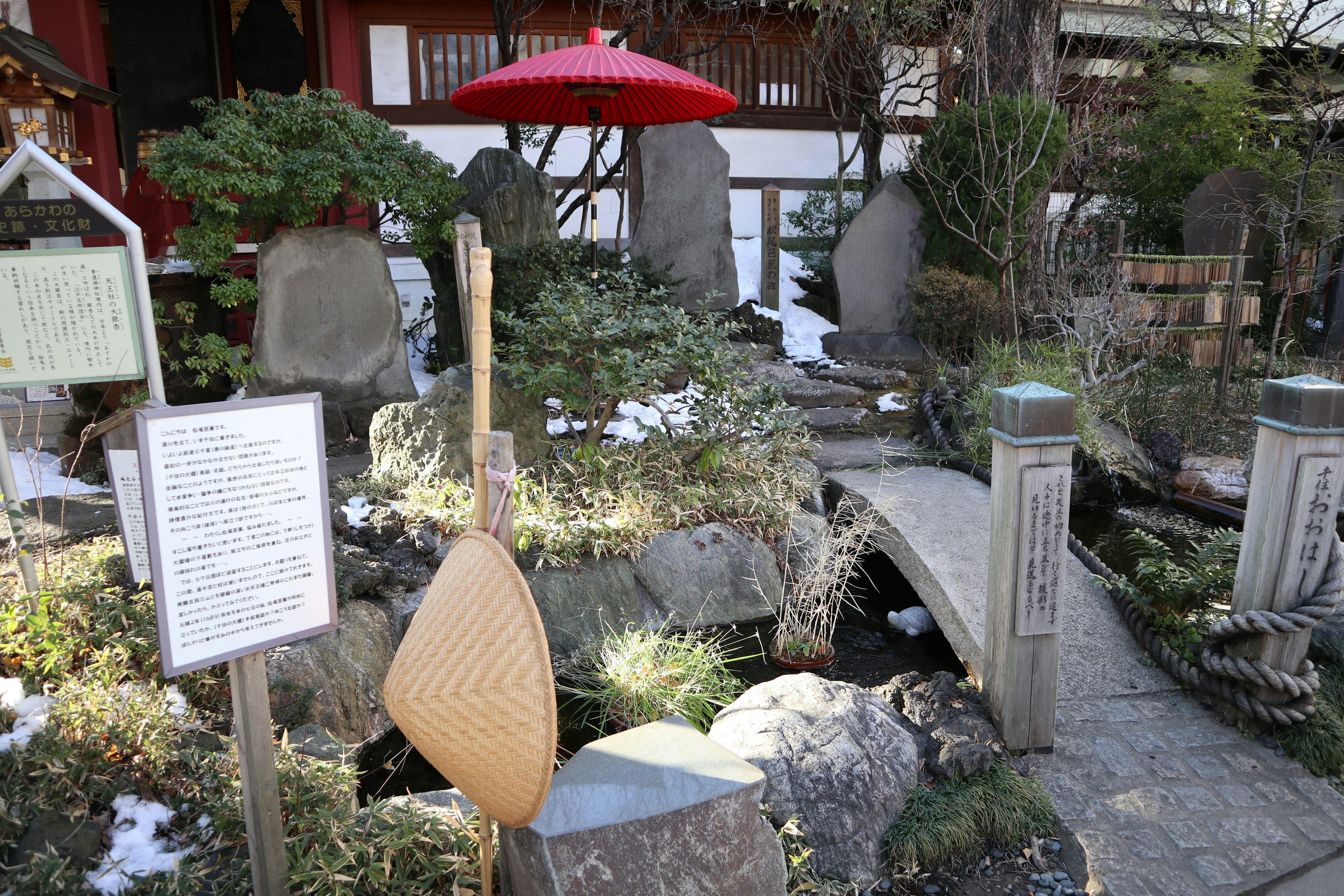 日本庭園の風景に赤い傘と小さな橋が見える