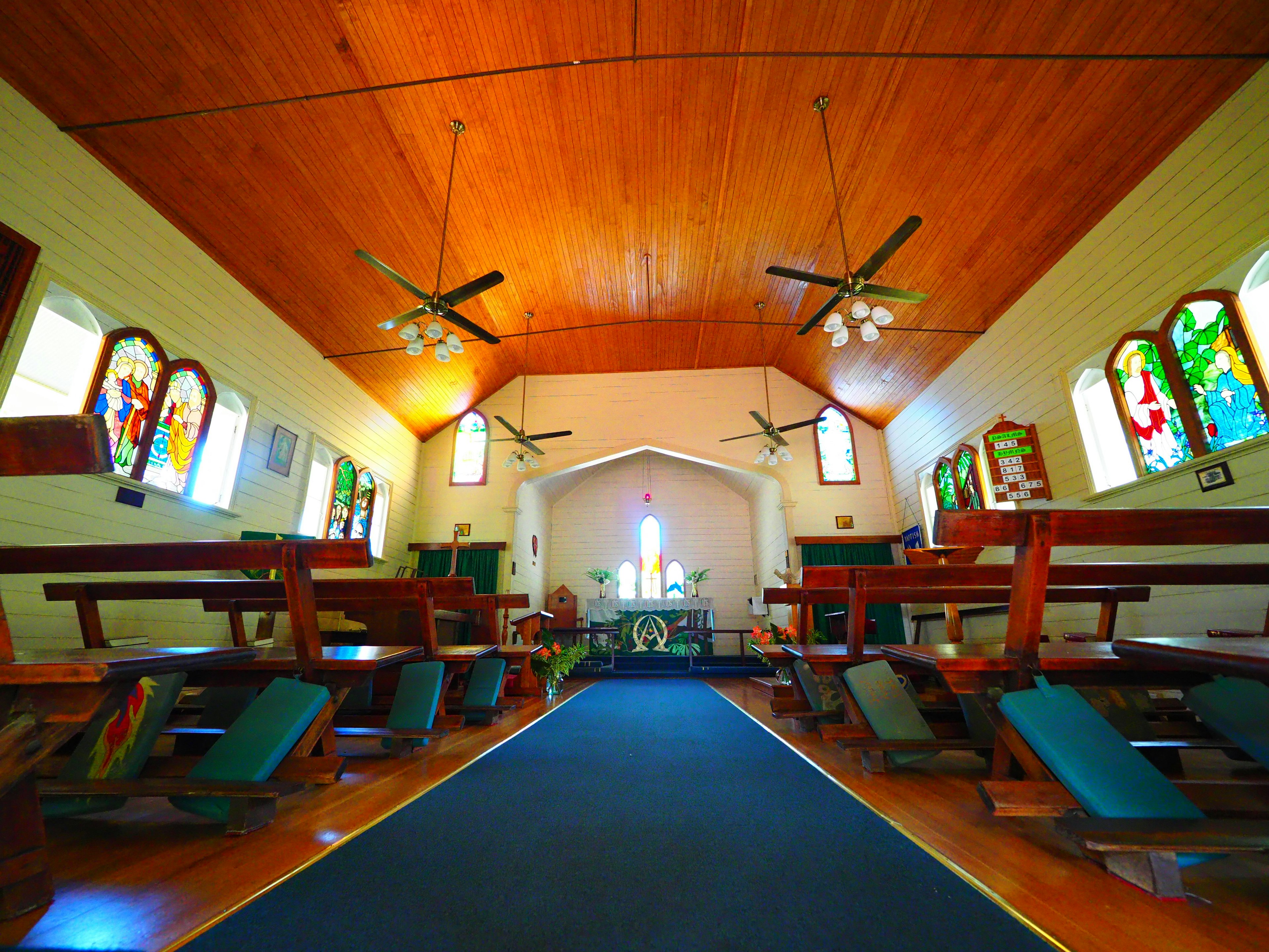 Interno di una chiesa con vetrate colorate panchine in legno disposte e un altare al centro