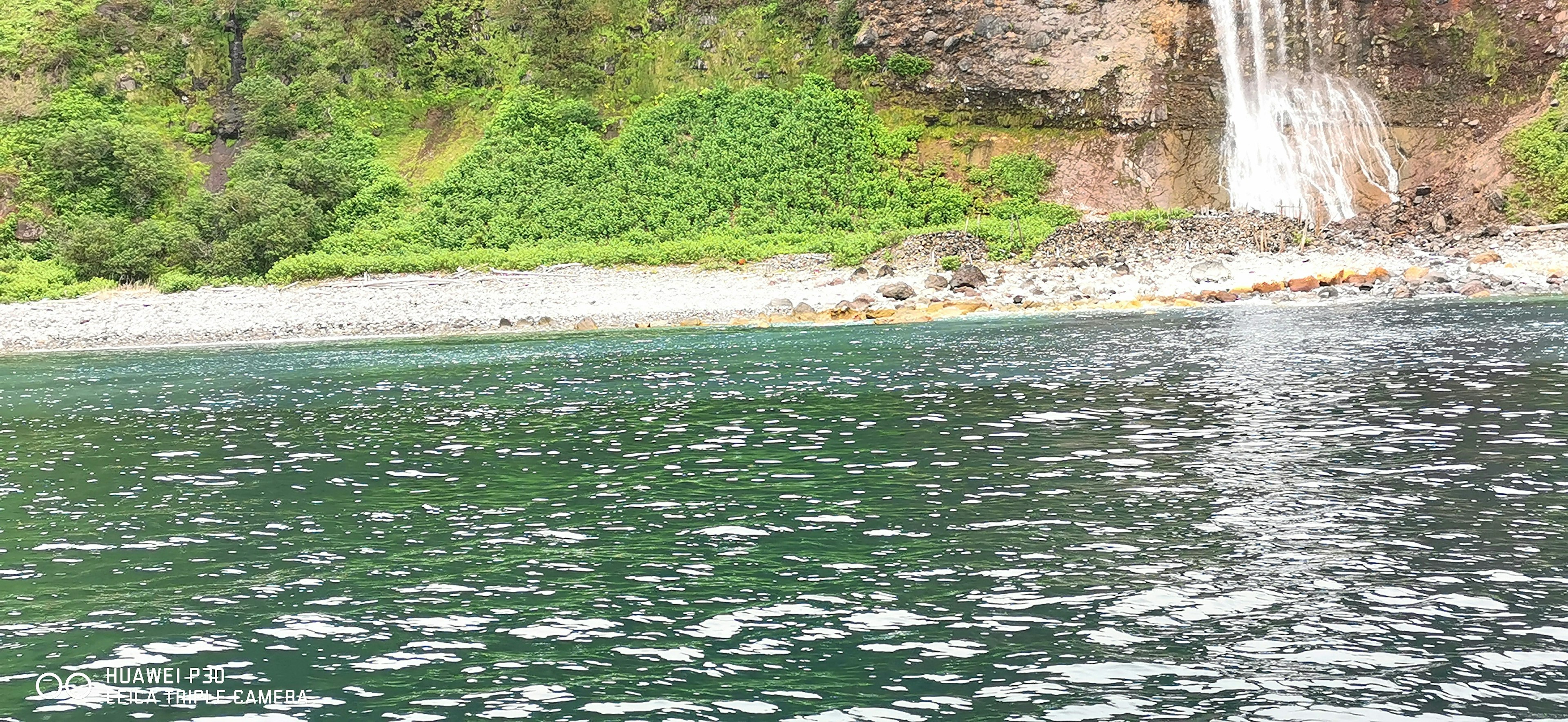 緑の丘と滝がある静かな海の風景