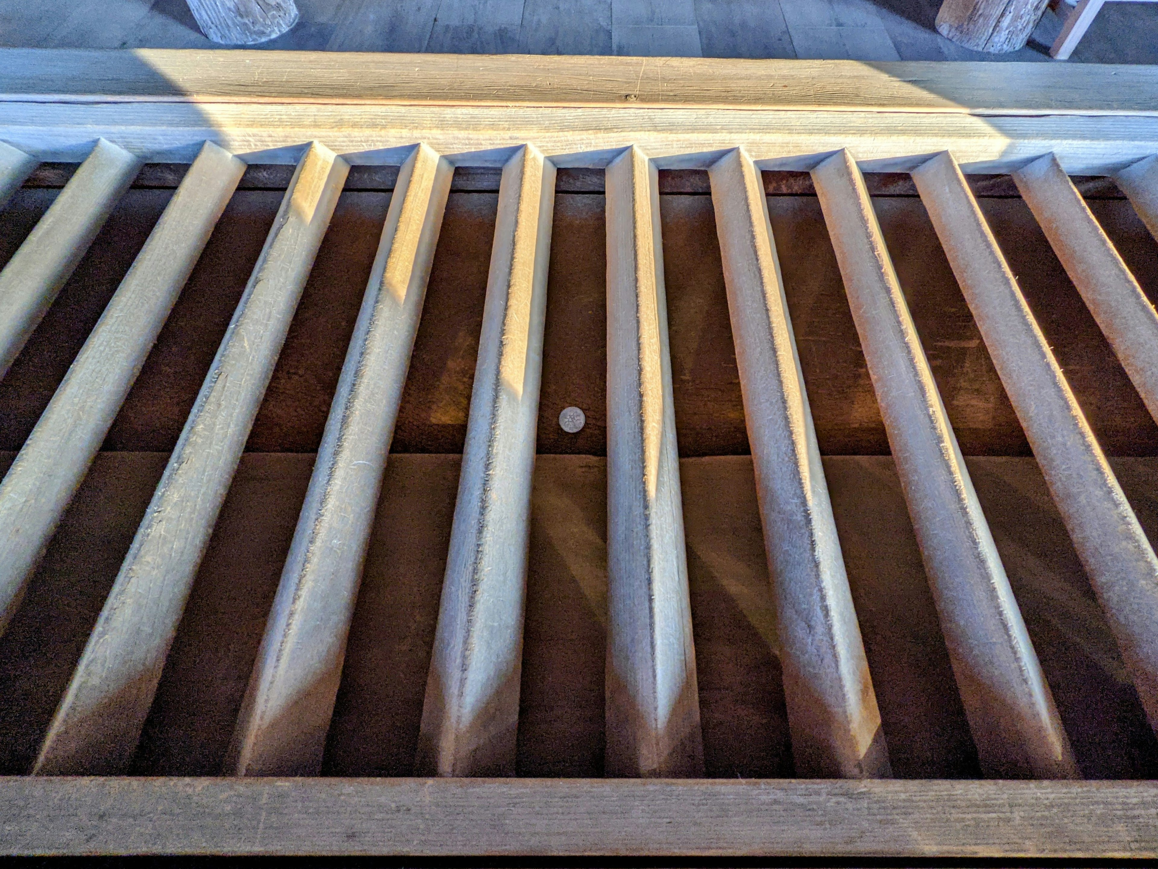 Wooden slats arranged on a floor with a small white ball