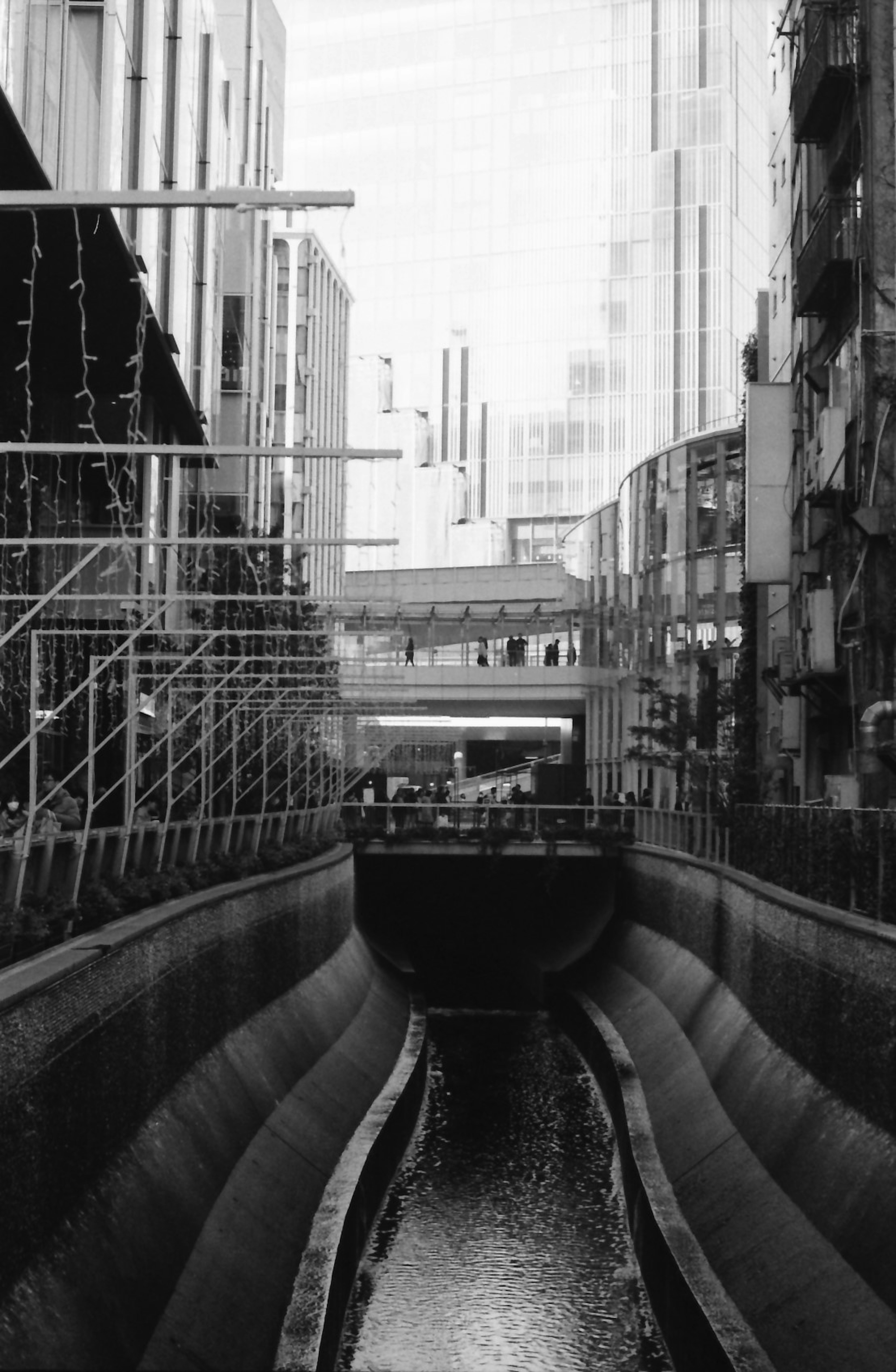 都市の狭い水路と高層ビルが見えるモノクロの風景