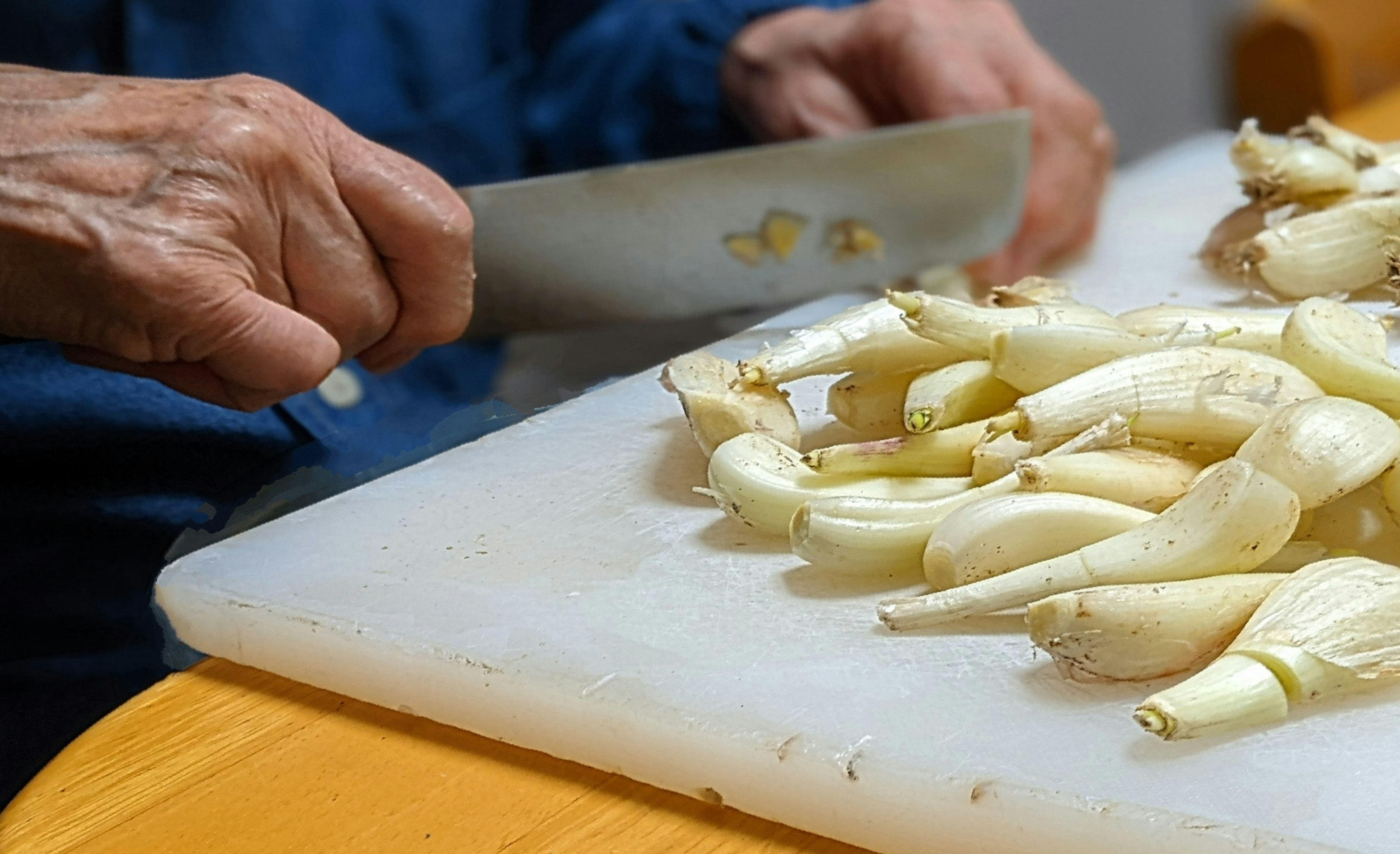 Mains coupant des légumes blancs sur une planche à découper avec un couteau