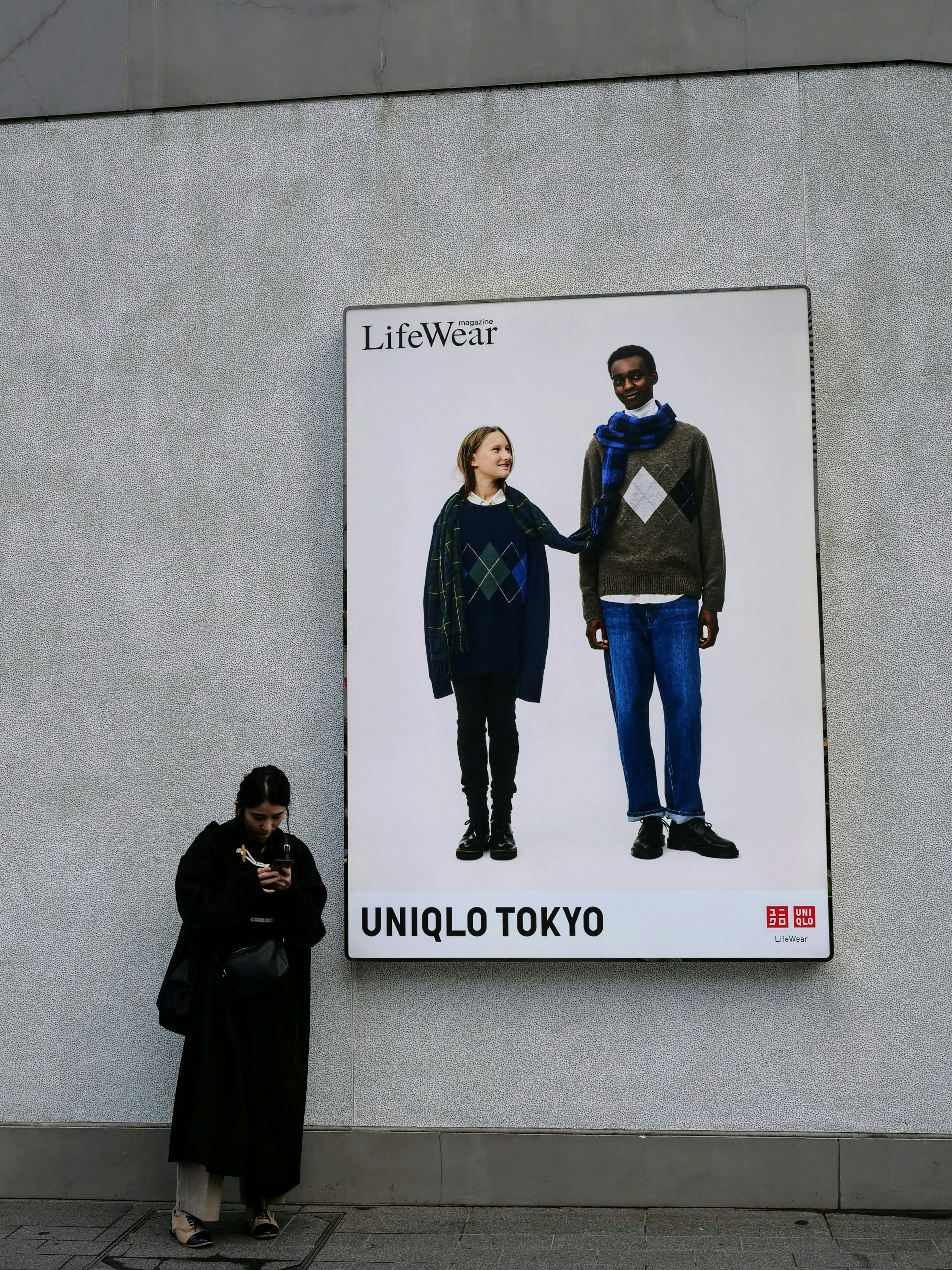 Dos modelos en un anuncio de Uniqlo Tokyo con una mujer en suéter y un hombre en suéter y pantalones