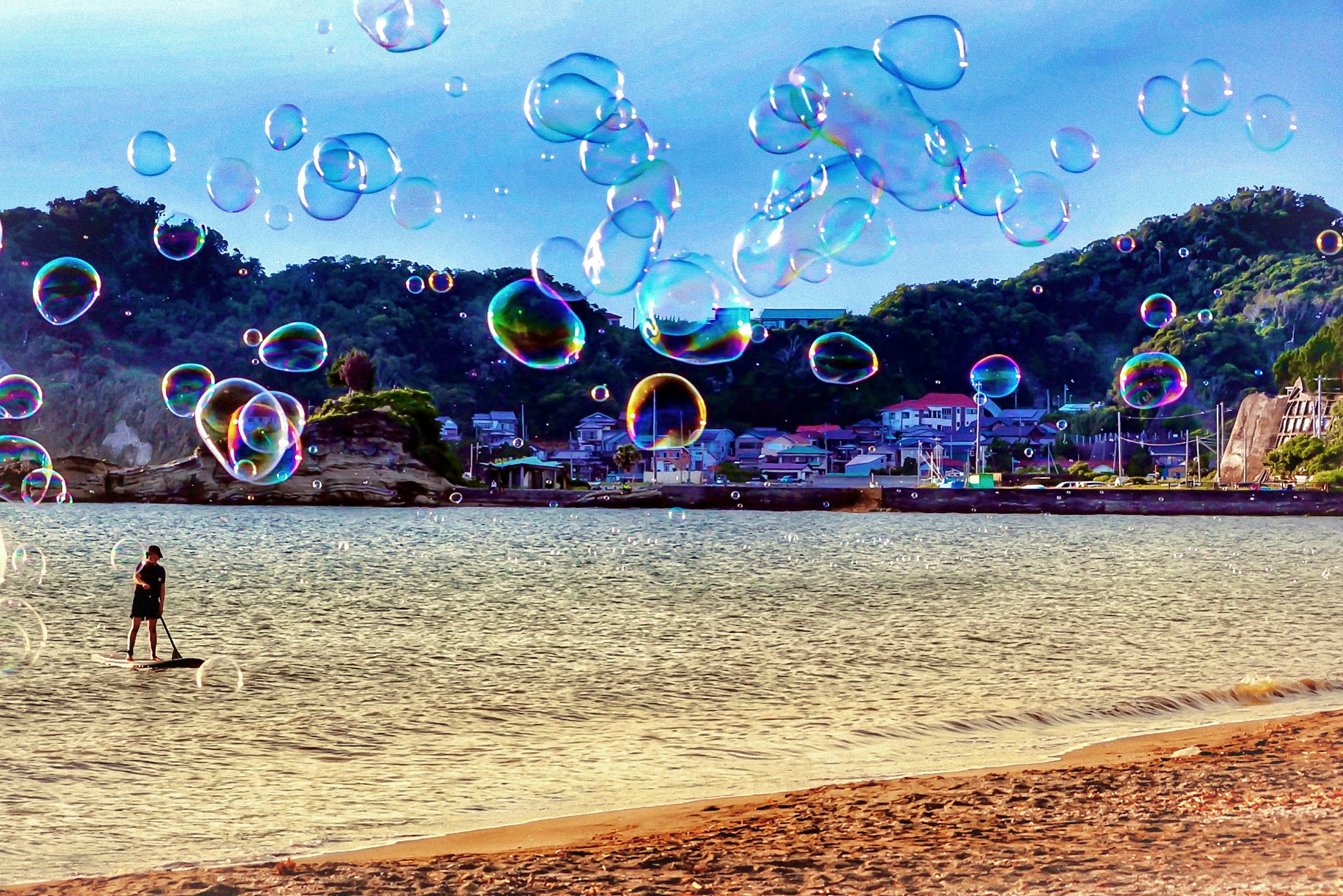 Una vista panoramica della spiaggia con bolle fluttuanti e la silhouette di una persona