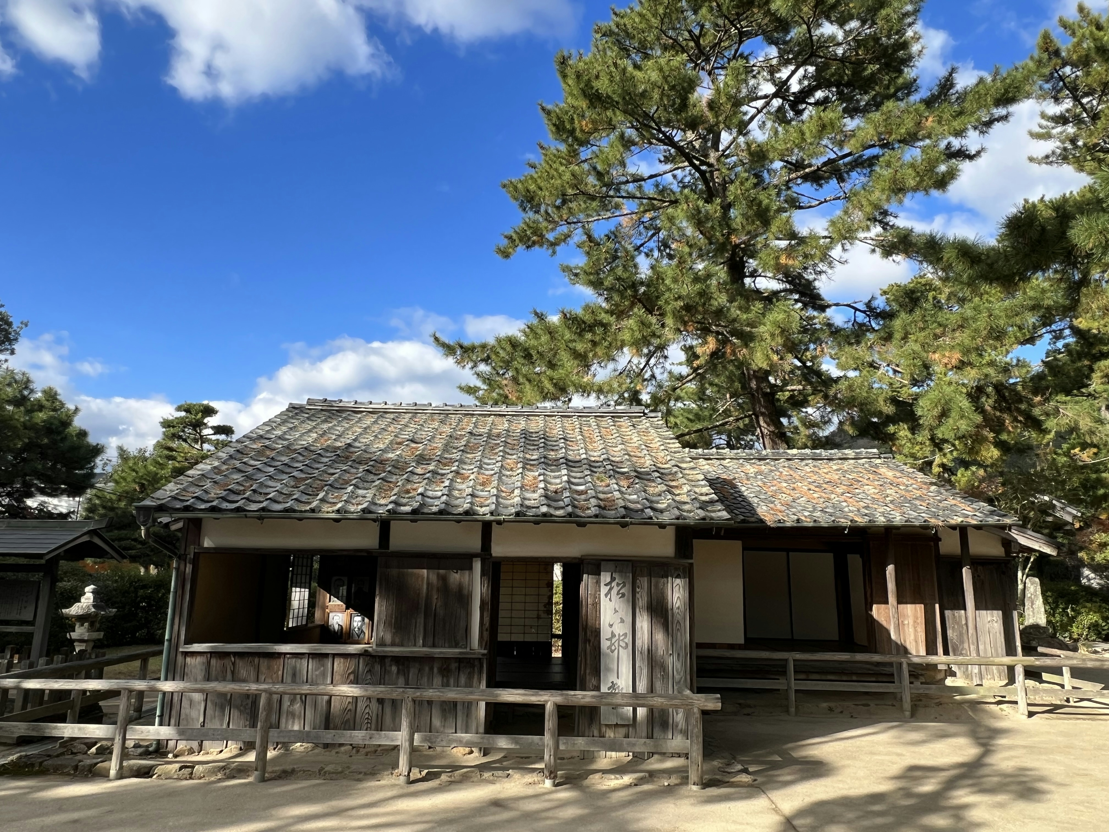 Vista exterior de una casa japonesa antigua bajo un pino