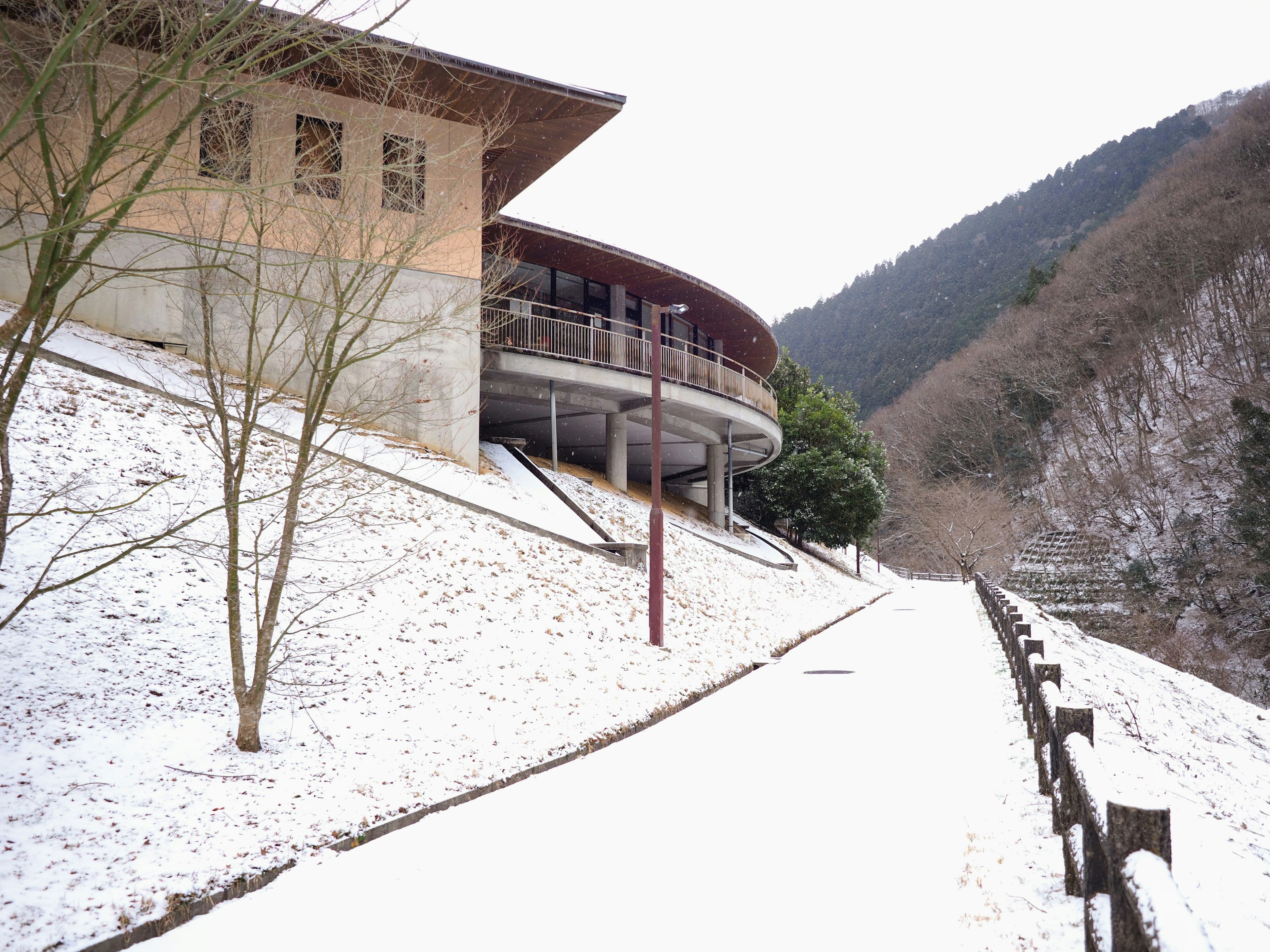 Modernes Gebäude neben einem schneebedeckten Weg mit Bergkulisse