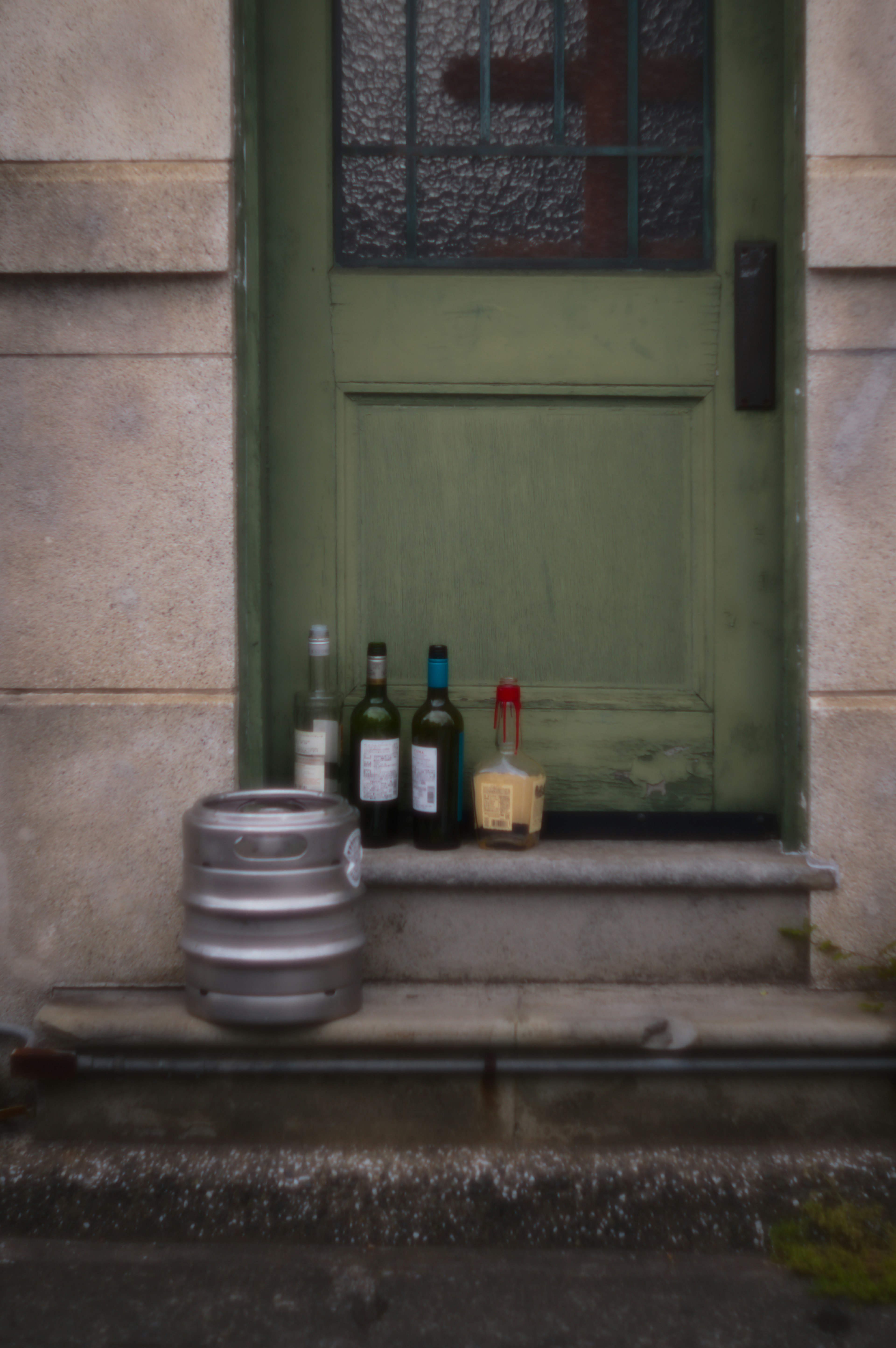 Wine bottles and a wooden container placed in front of a green door