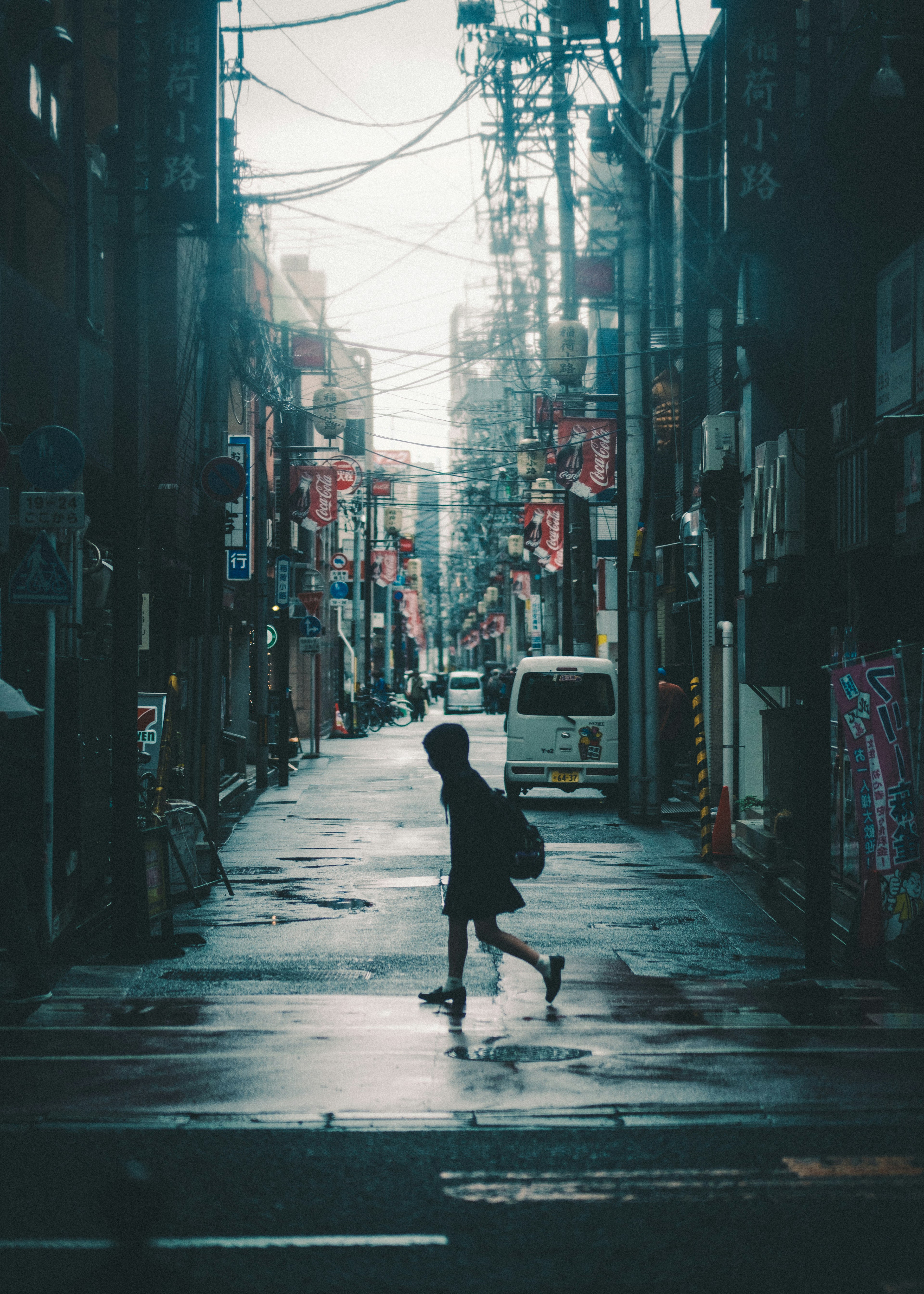 Silhouette of a person walking in a rain-soaked alley