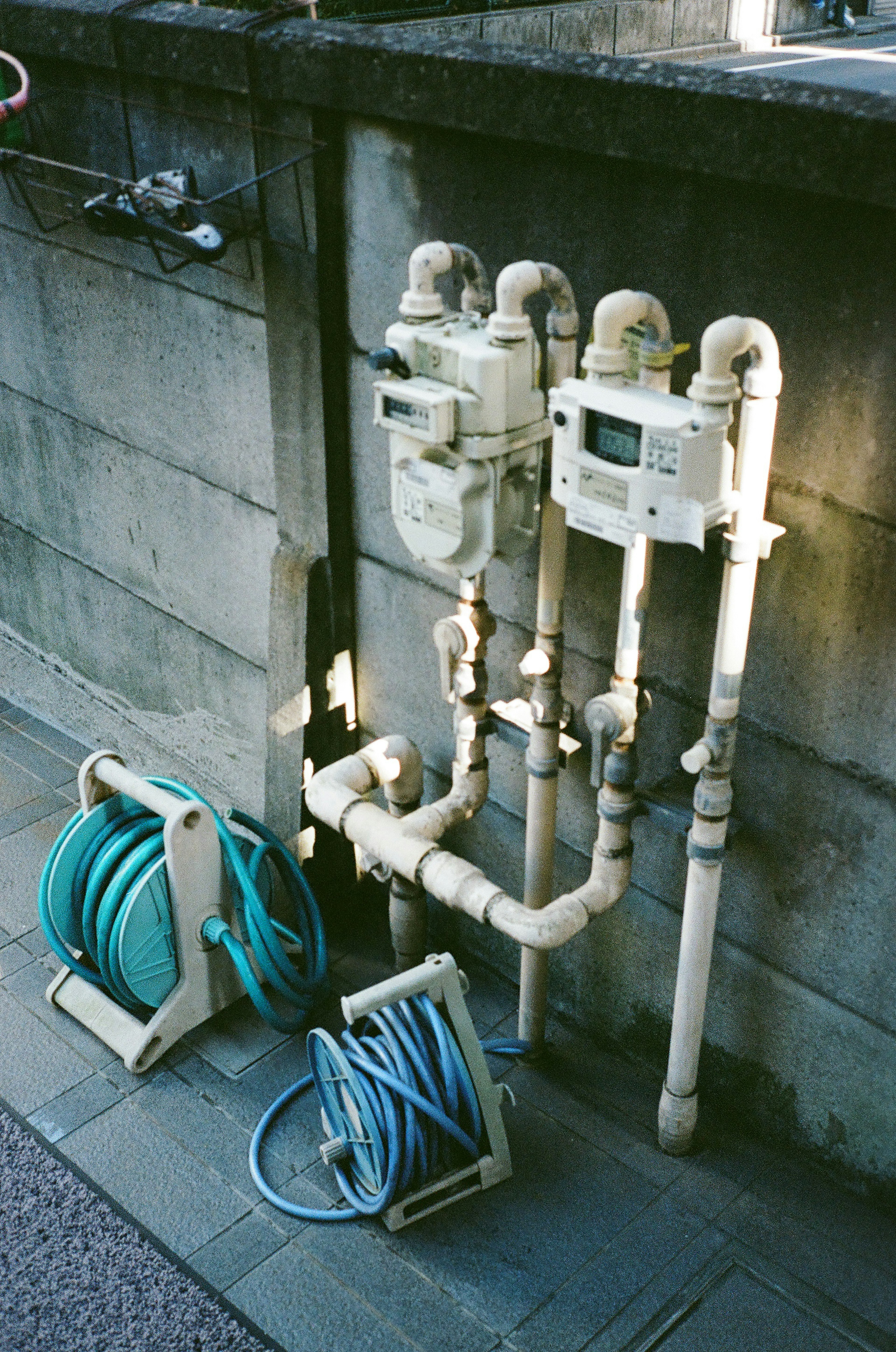 Contadores de agua y tuberías montados en una pared con enrolladores de manguera