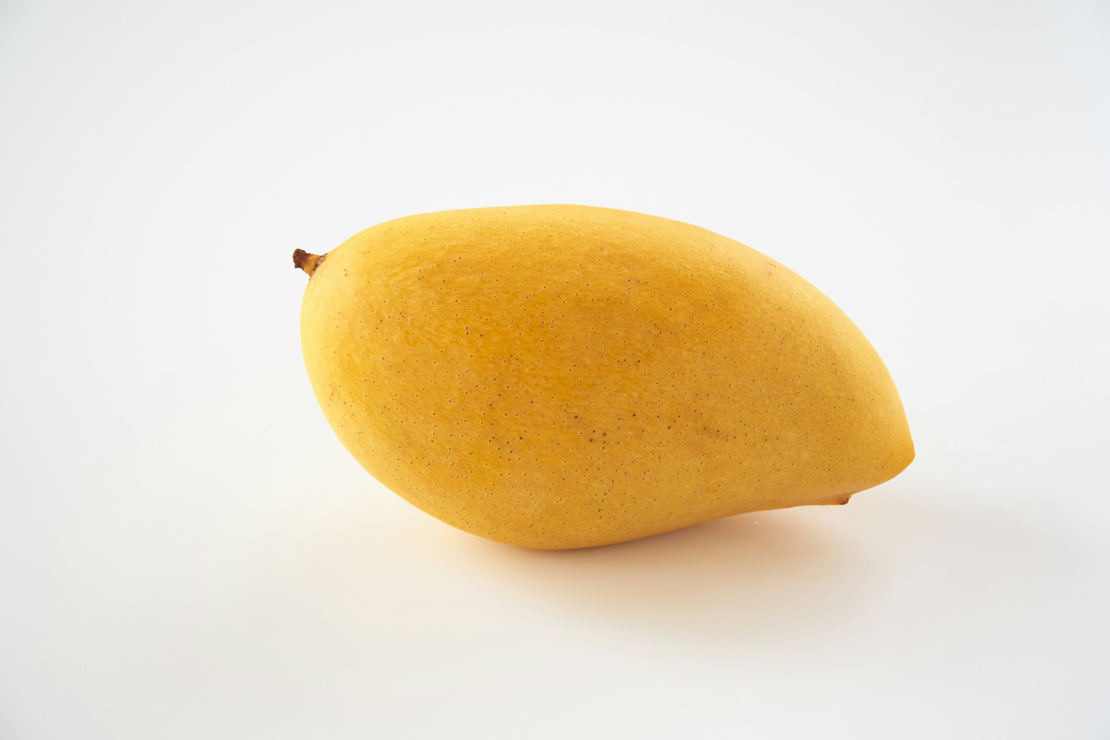 Eine leuchtend gelbe Mango auf einem weißen Hintergrund