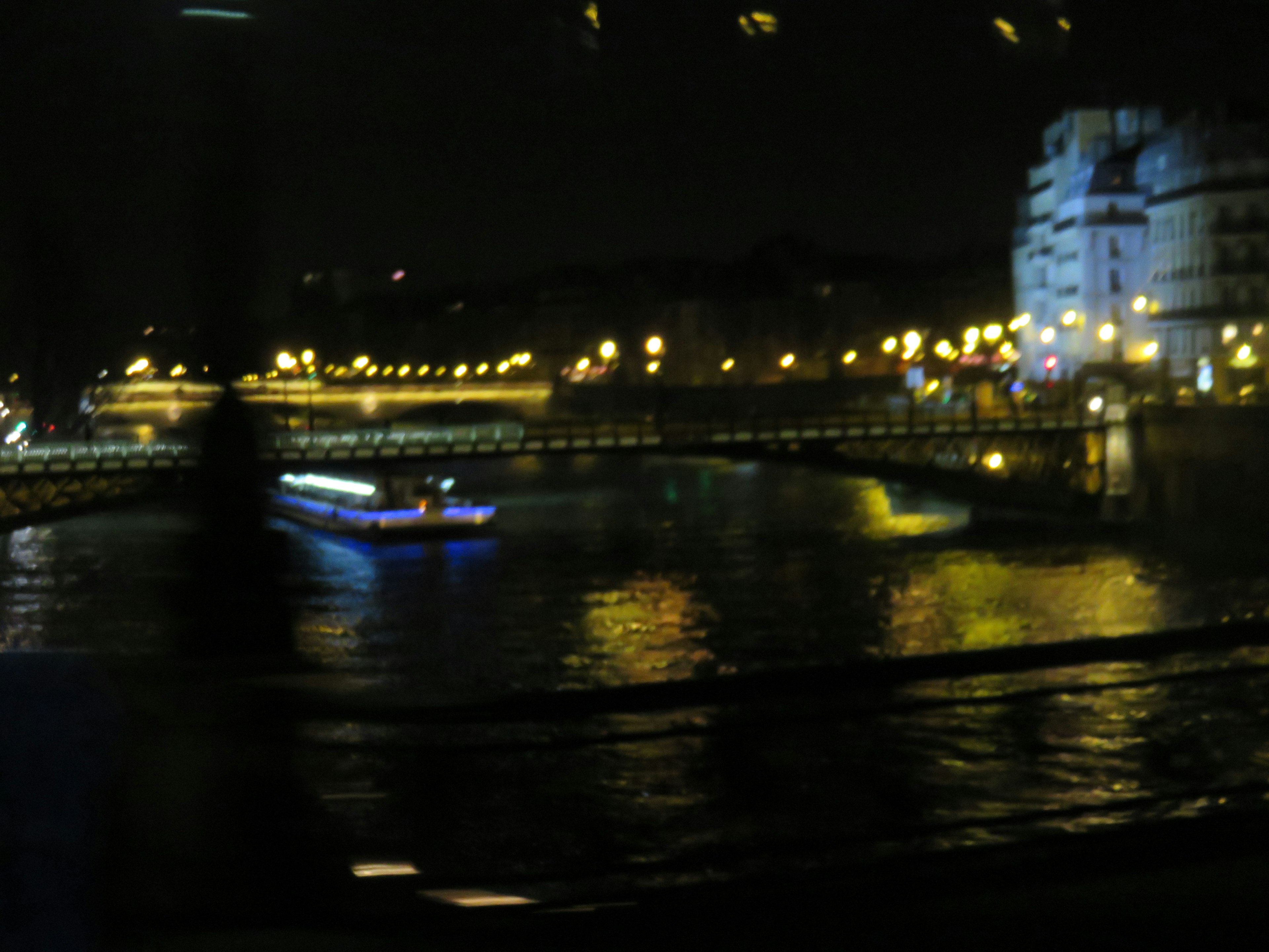 Barco en el río Sena por la noche con luces centelleantes