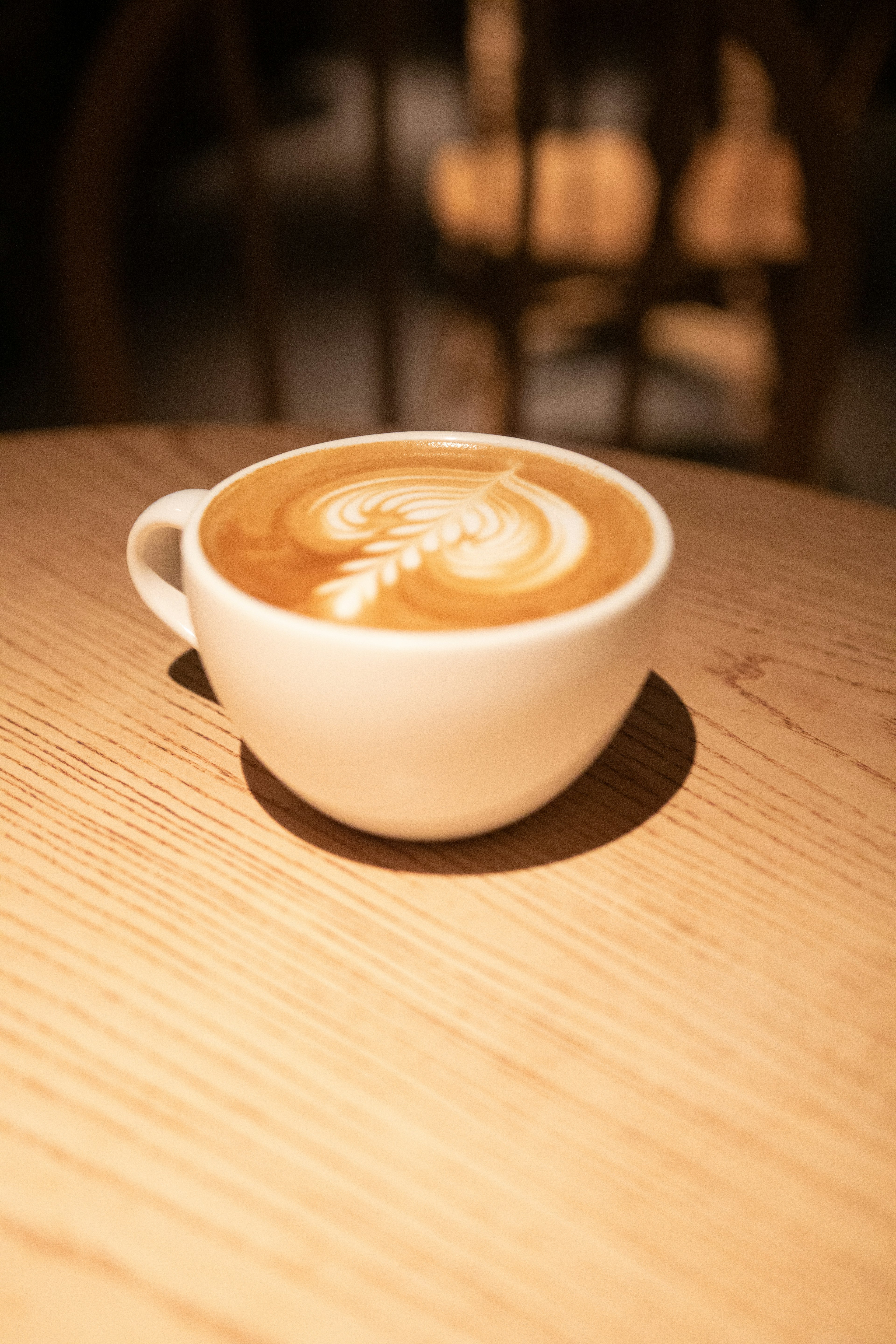 A latte art coffee in a white cup placed on a wooden table