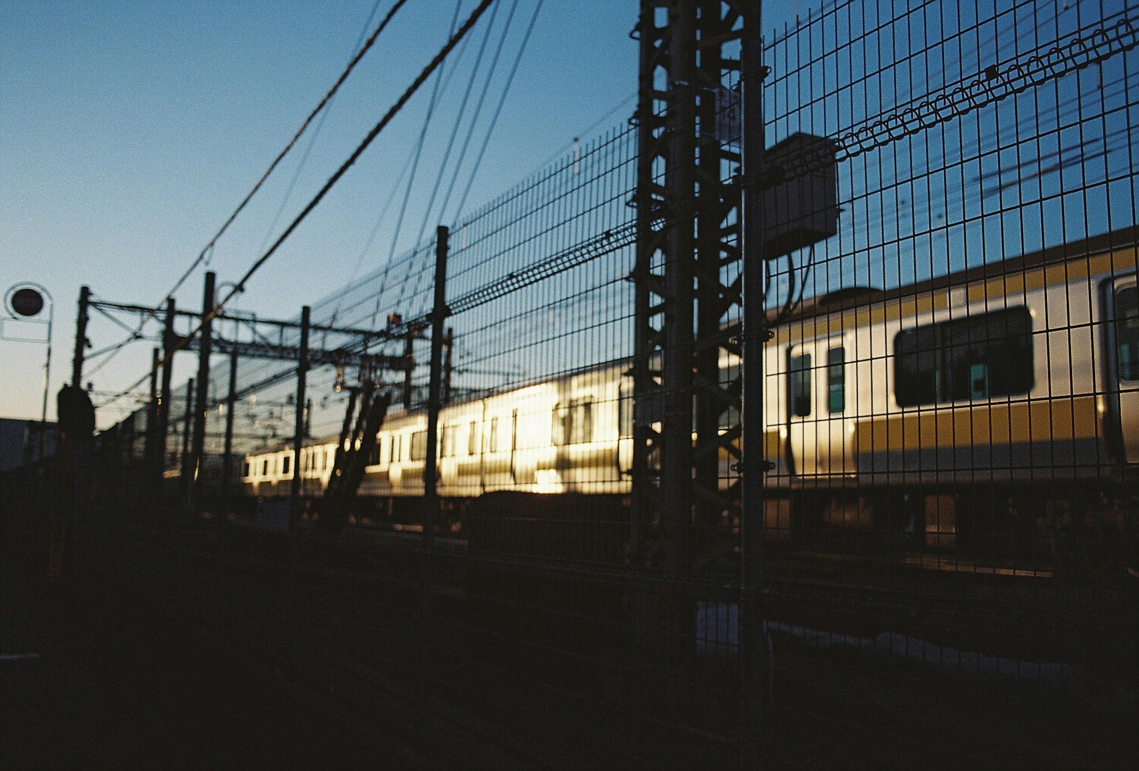 夕暮れ時の線路に沿った電車のシルエットと鉄塔