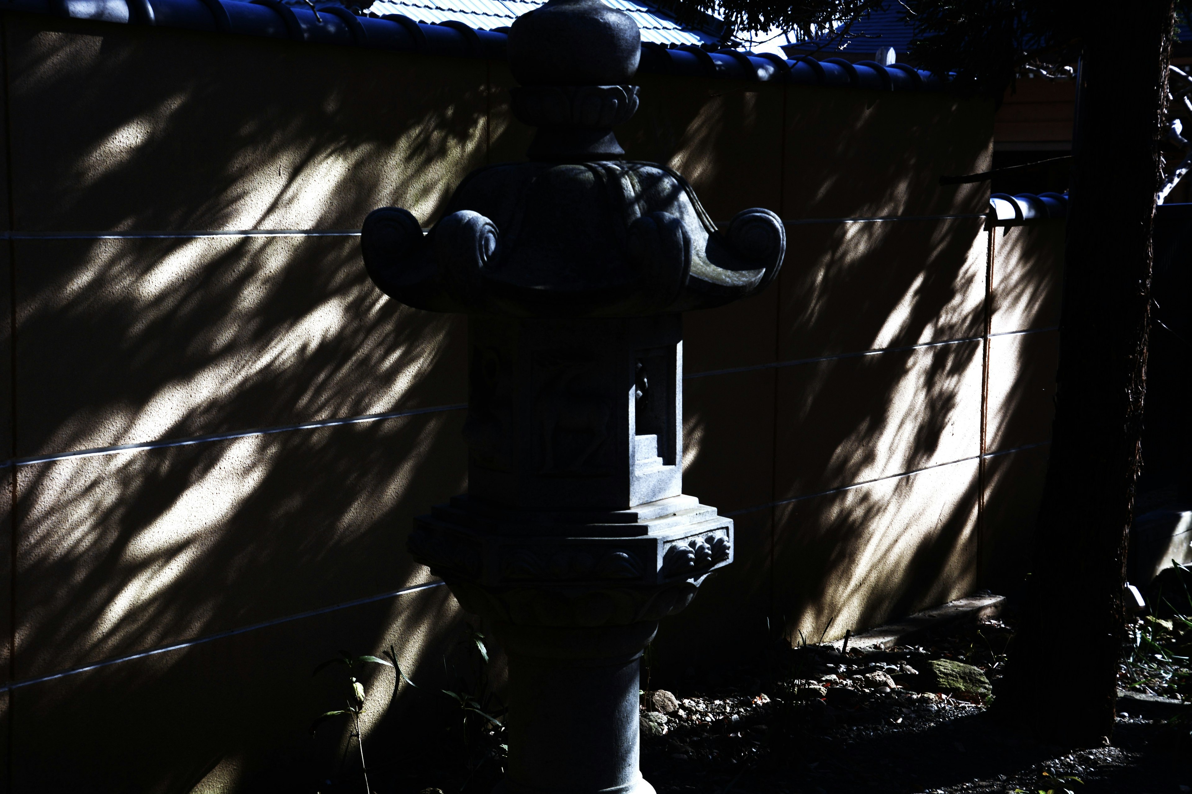 An old water fountain in shadows with a wall in the background