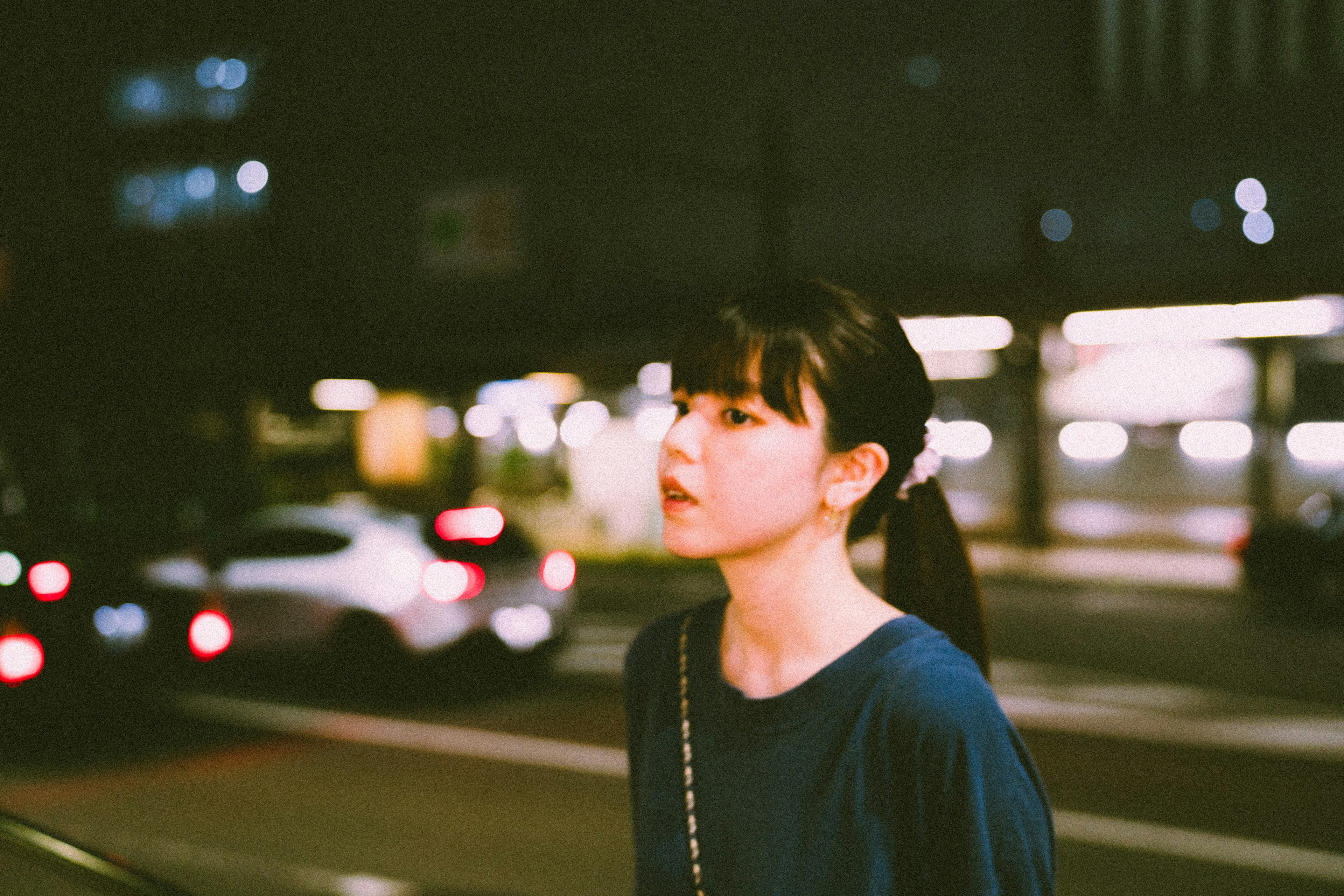 Portrait of a woman walking in the city at night with blurred car lights in the background