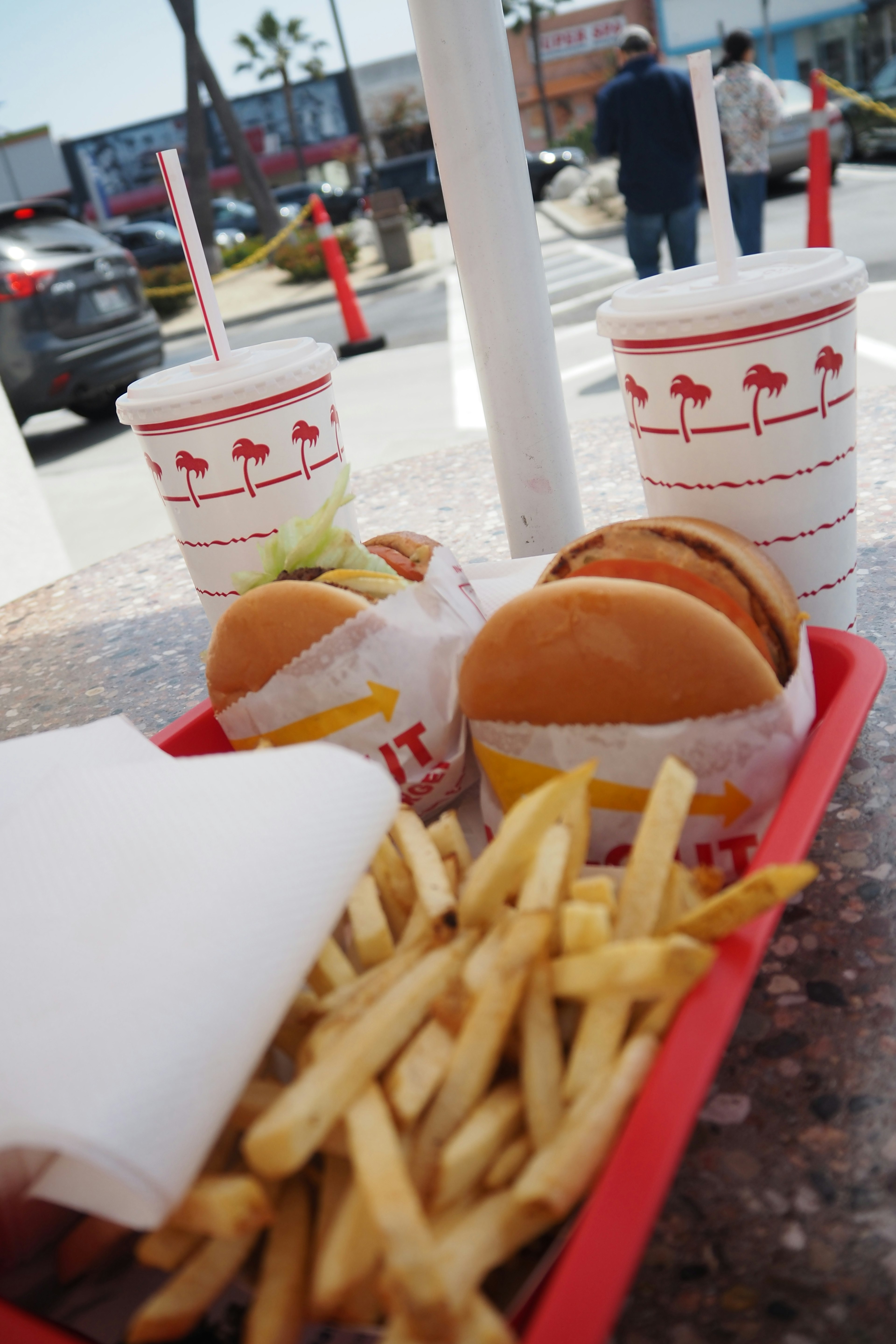 เบอร์เกอร์และมันฝรั่งทอดจาก In-N-Out เสิร์ฟในถาดสีแดงบนโต๊ะ