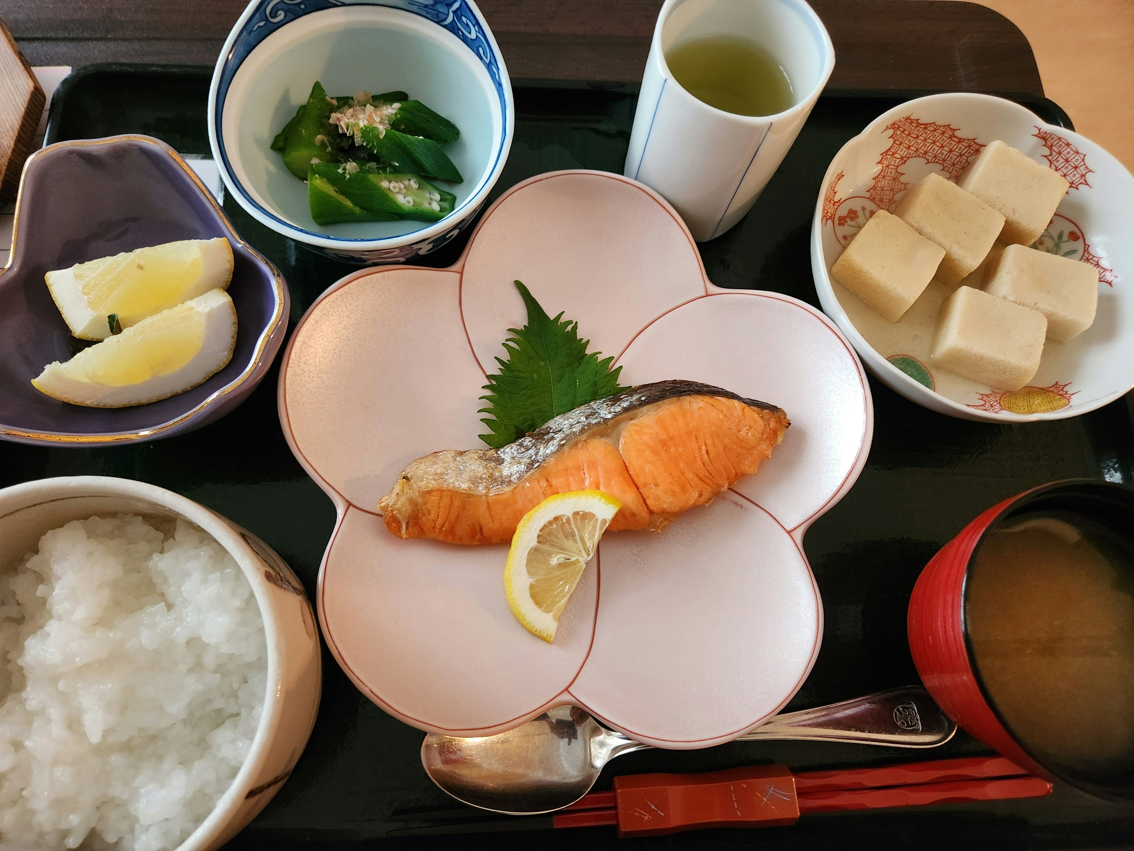 Repas japonais avec du saumon sur une assiette en forme de fleur de cerisier avec des tranches de citron et divers plats d'accompagnement