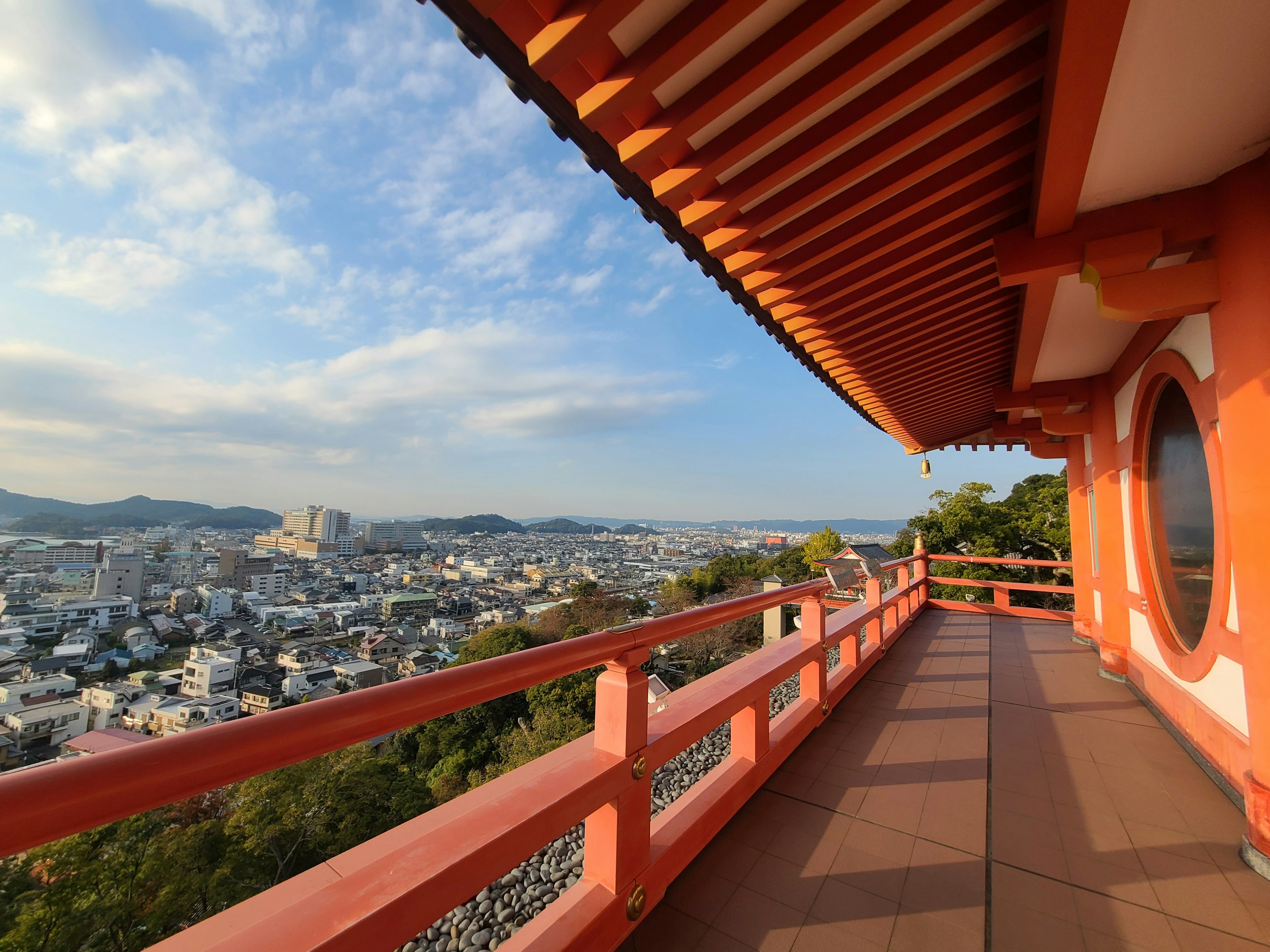 View from a red balcony overlooking a city and blue sky