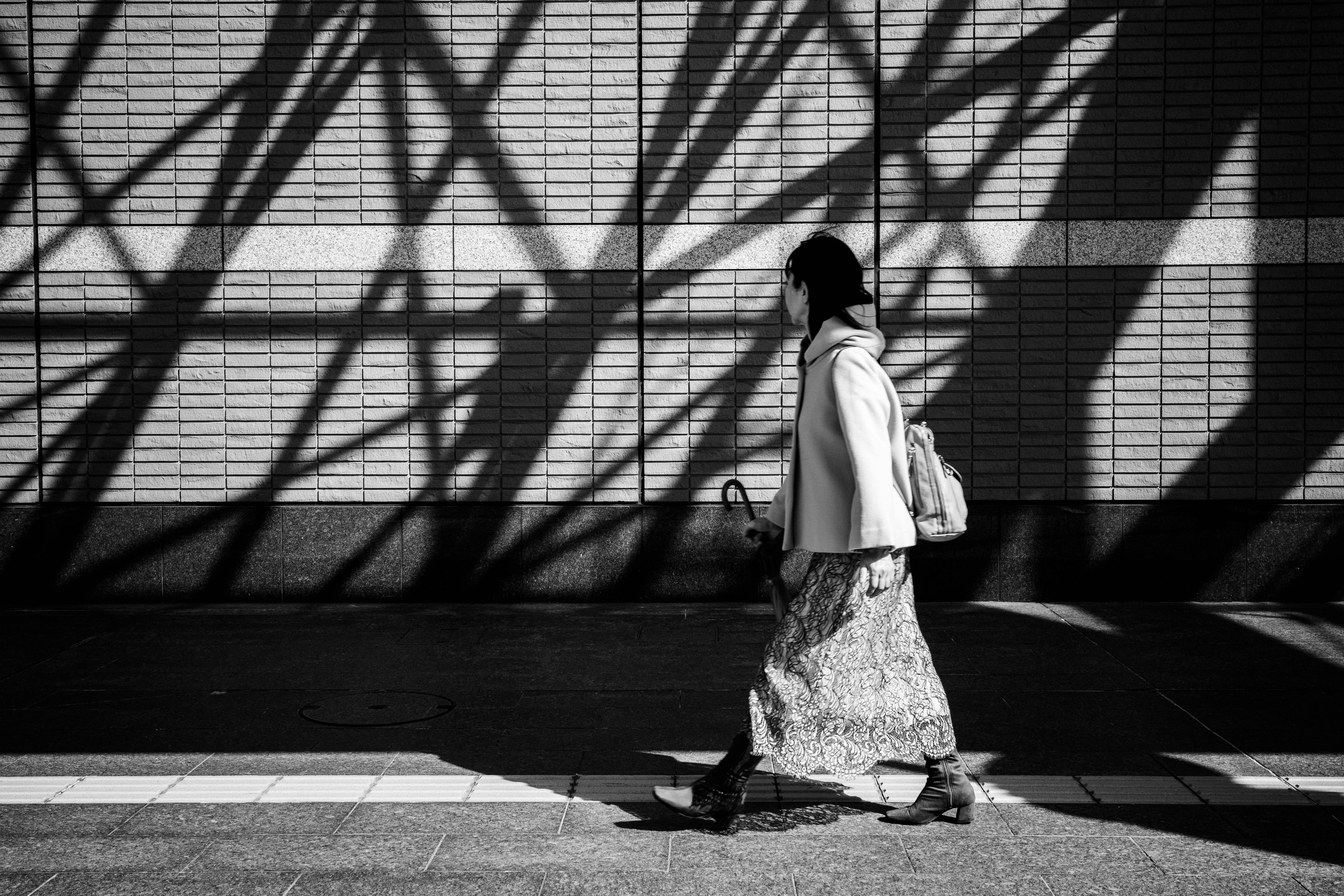 A woman in traditional clothing walking against a backdrop of striking shadows