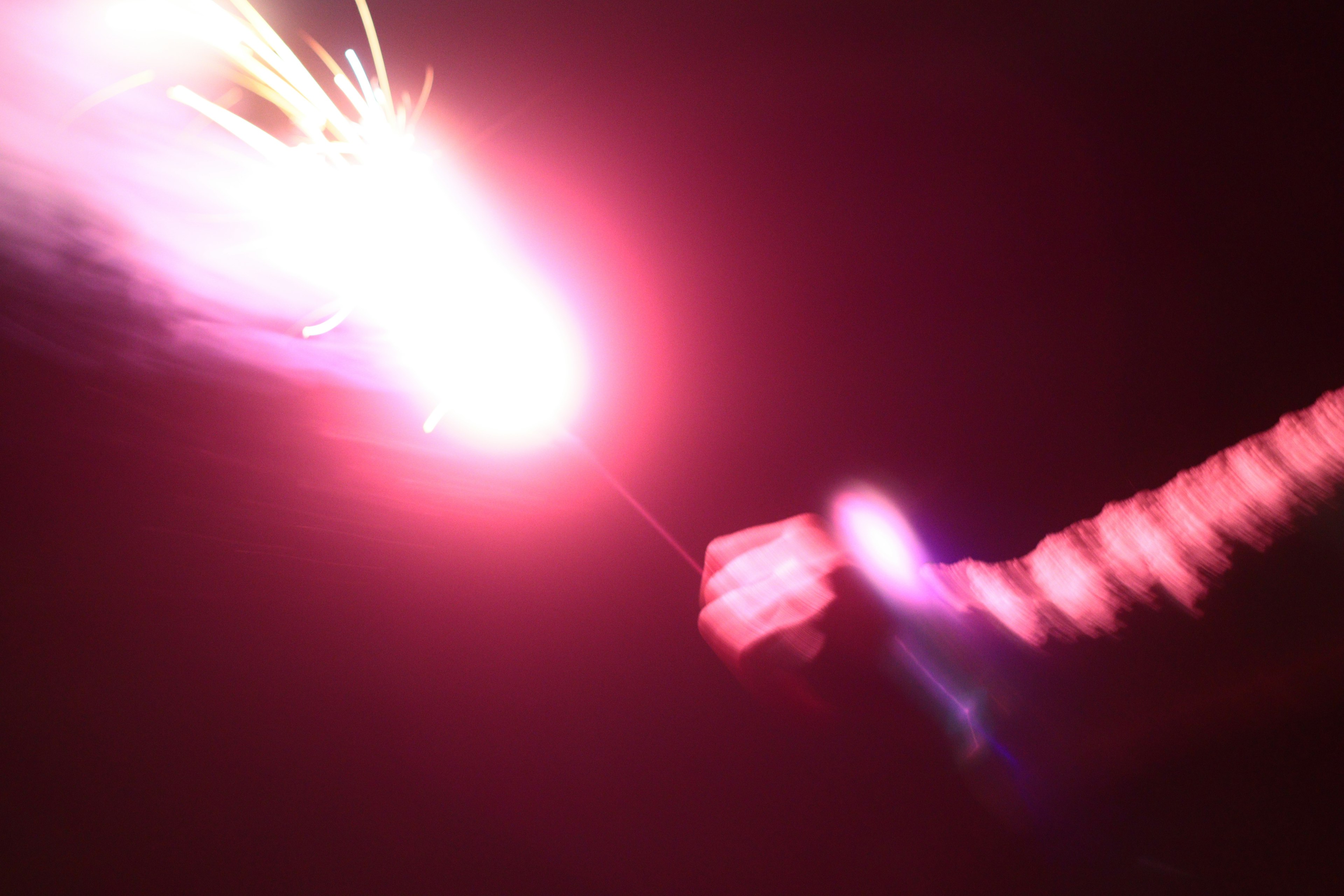 Bright red sparkler emitting light in a dark background