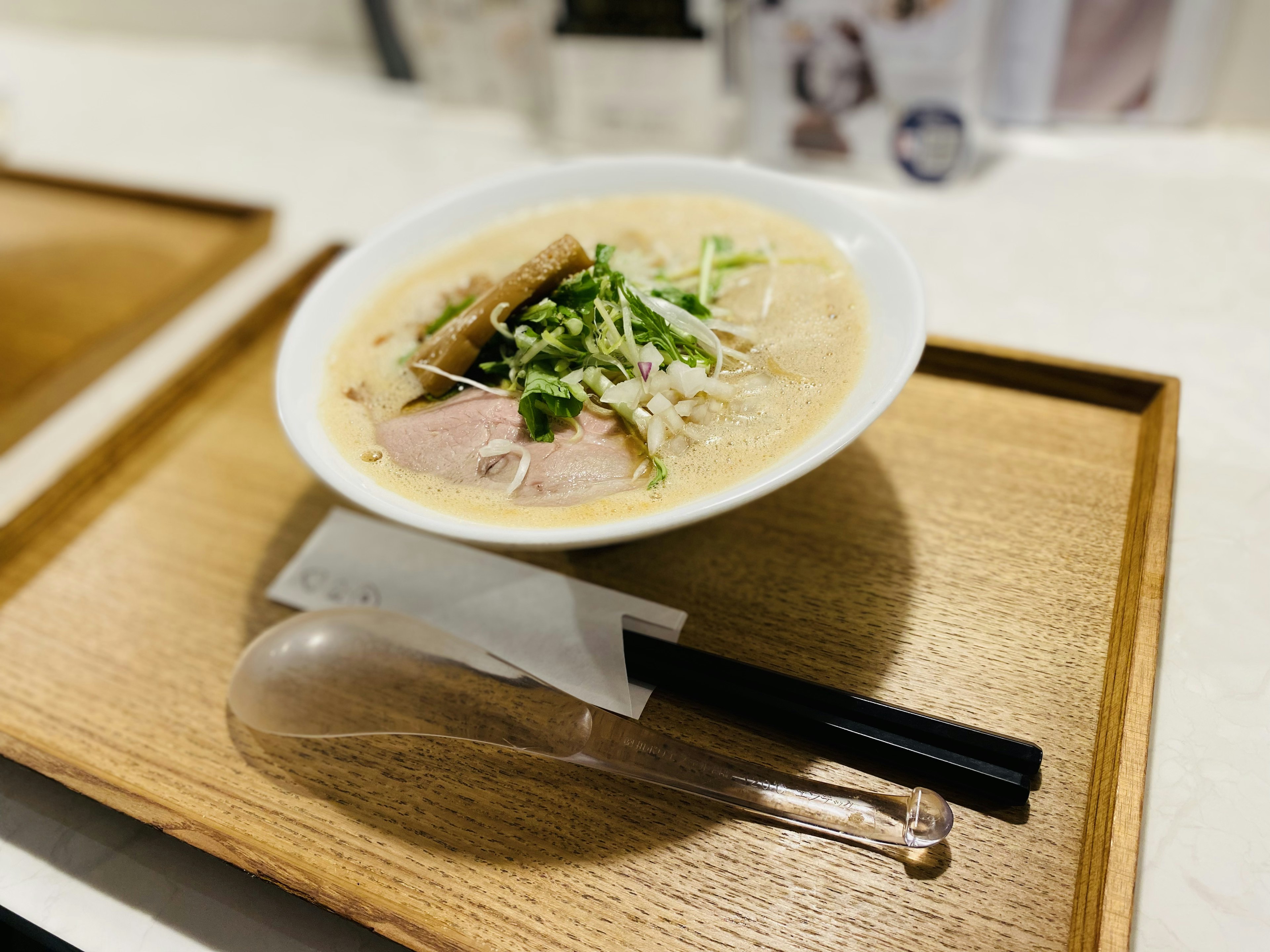 Una ciotola di ramen su un vassoio di legno con bacchette