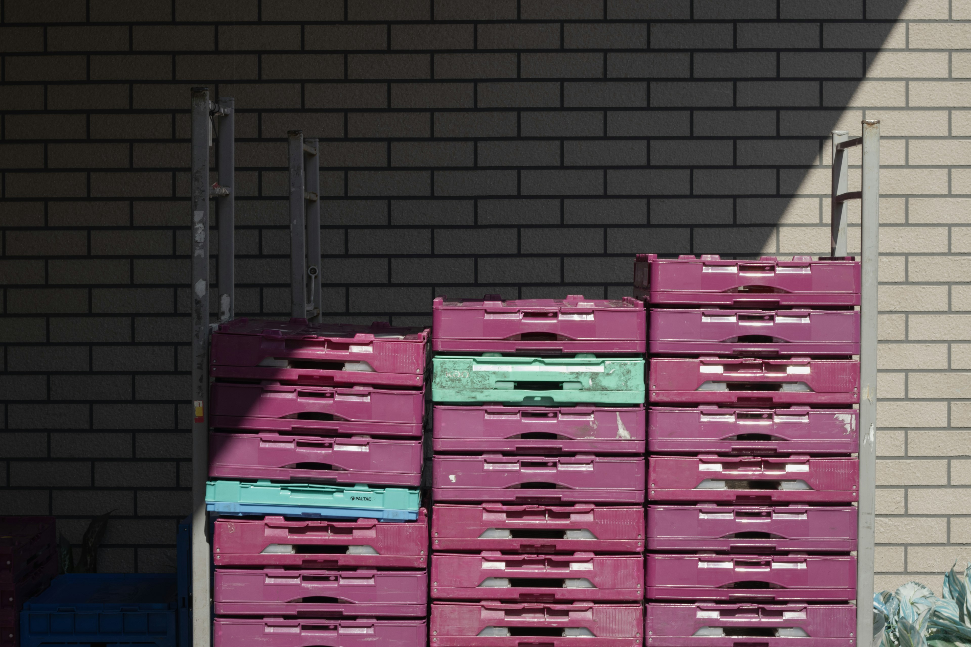 Stacked maroon plastic crates against a brick wall