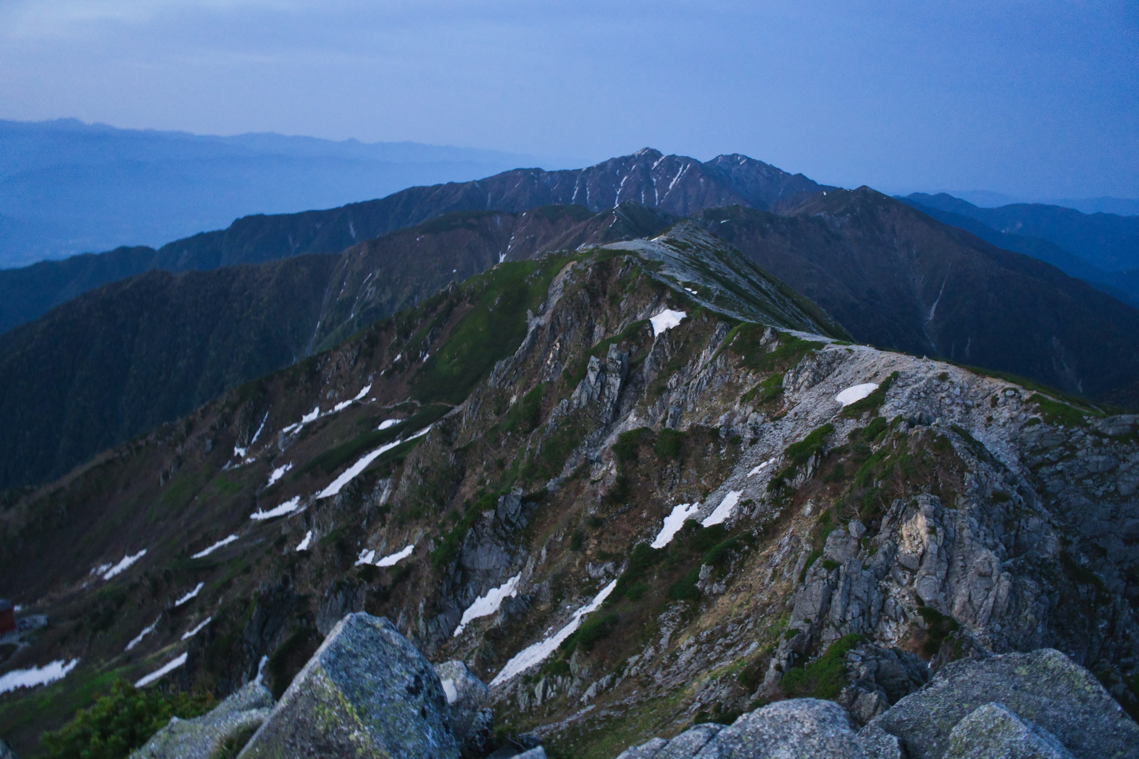 Evening scene of a mountain range under a blue sky