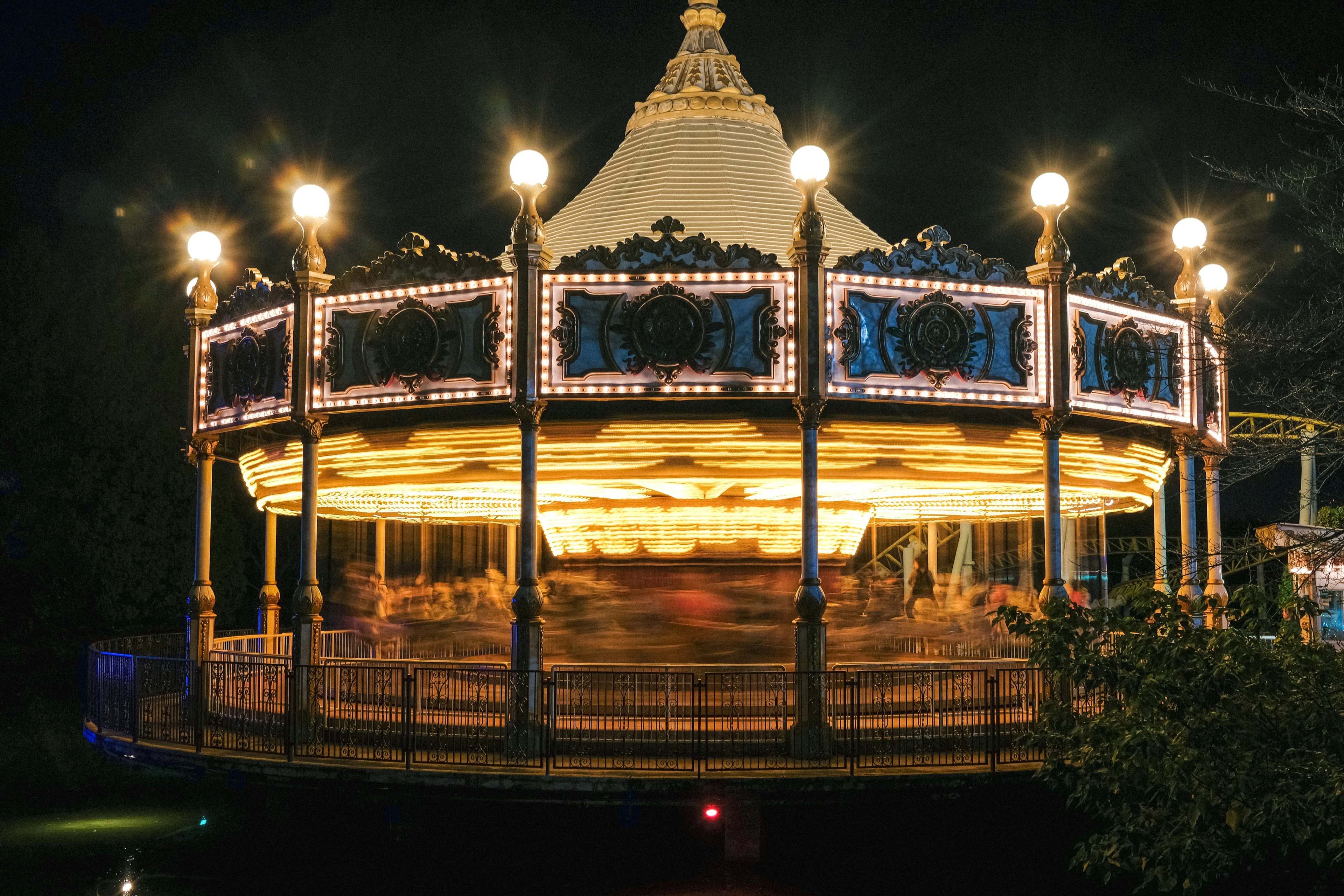 A carousel spinning at night with bright lights illuminating the surroundings