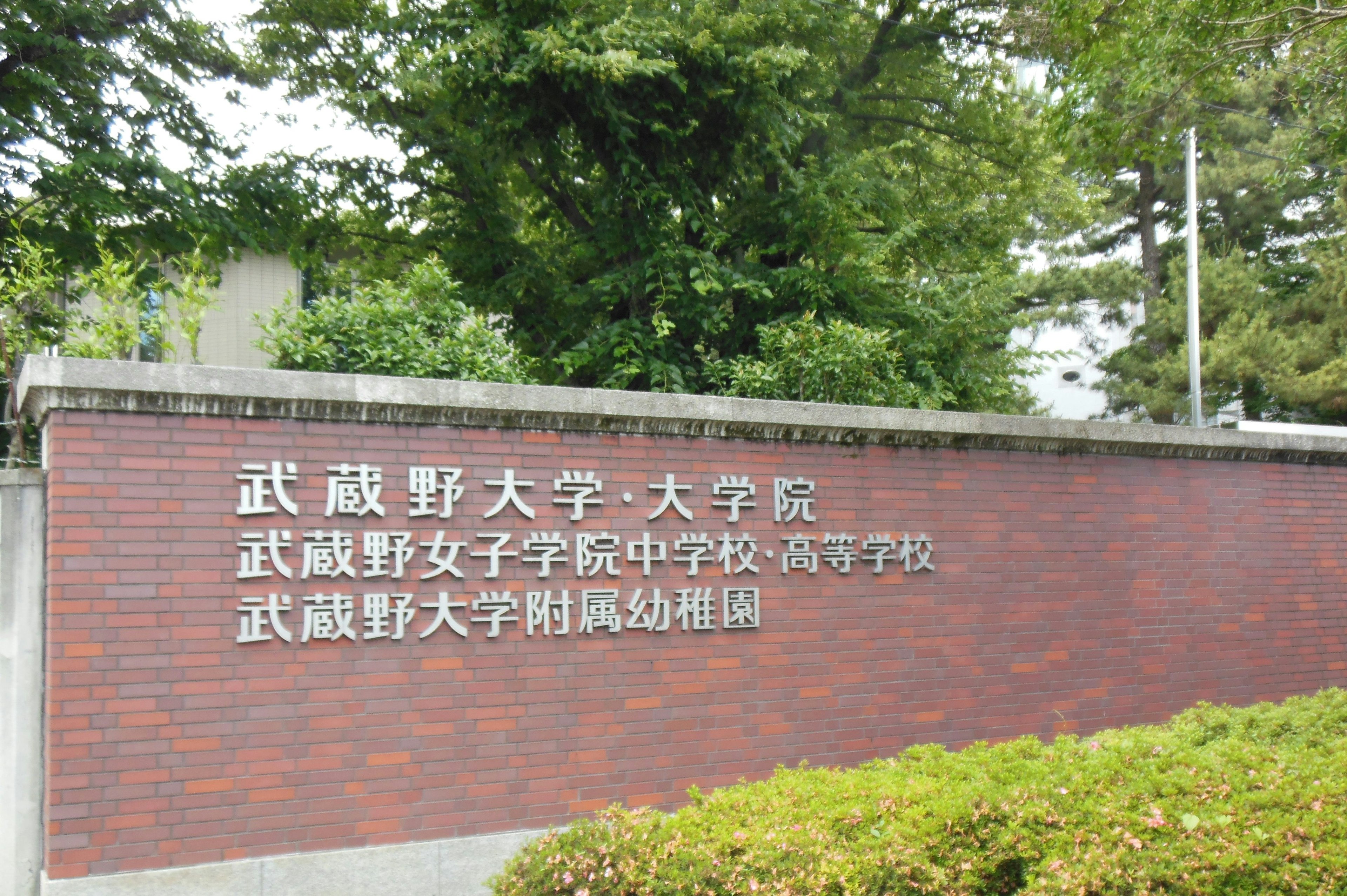 Signage of Musashino University with lush greenery in the background