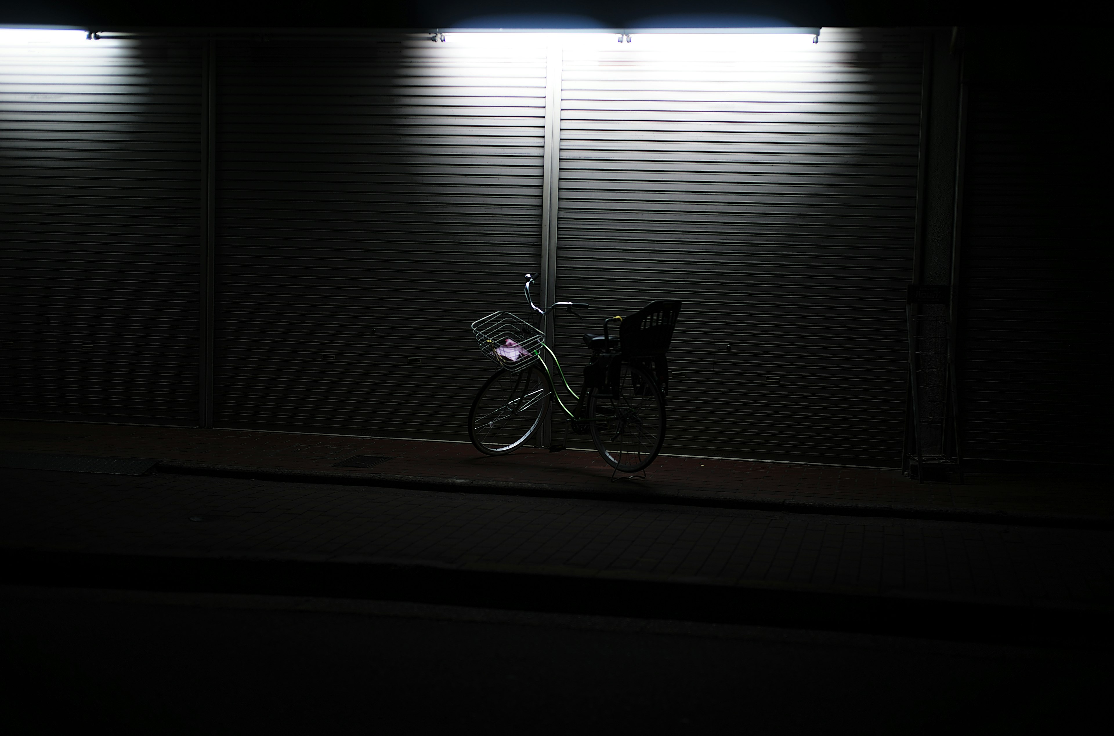 A bicycle illuminated by two bright lights against a dark background